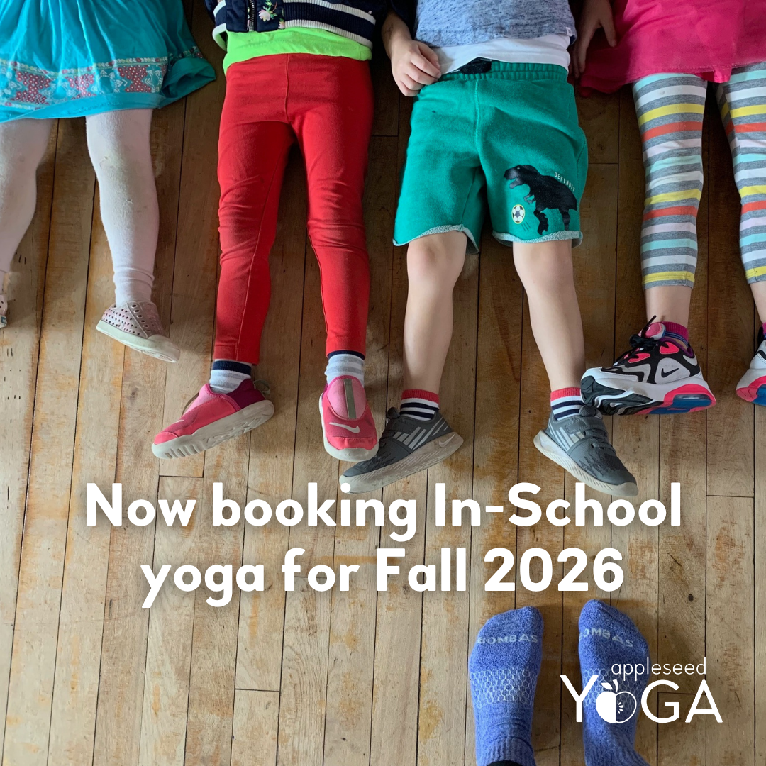 A row of kids lying on a wooden floor, you can only see their legs and feet, with the words 'Now Booking in-school yoga for Fall 2026' below