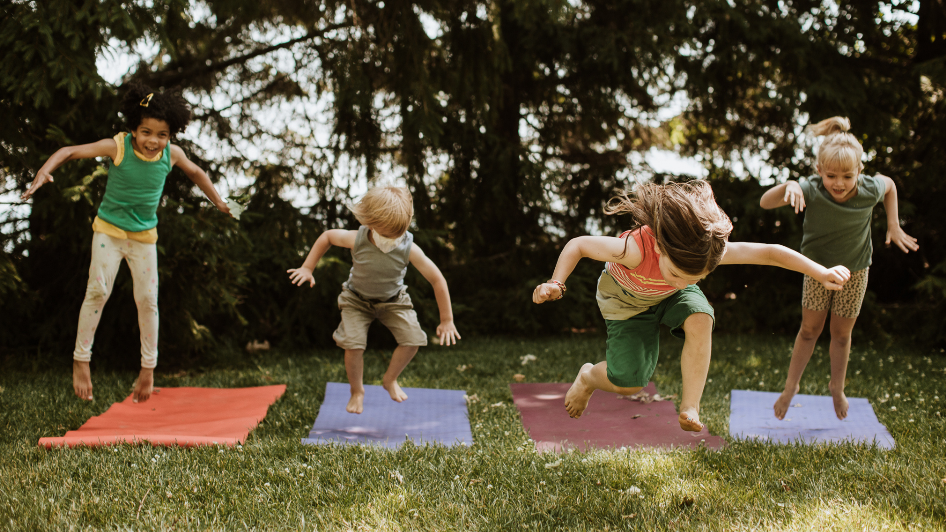 kids jumping up in the air above yoga mats spread out on grass