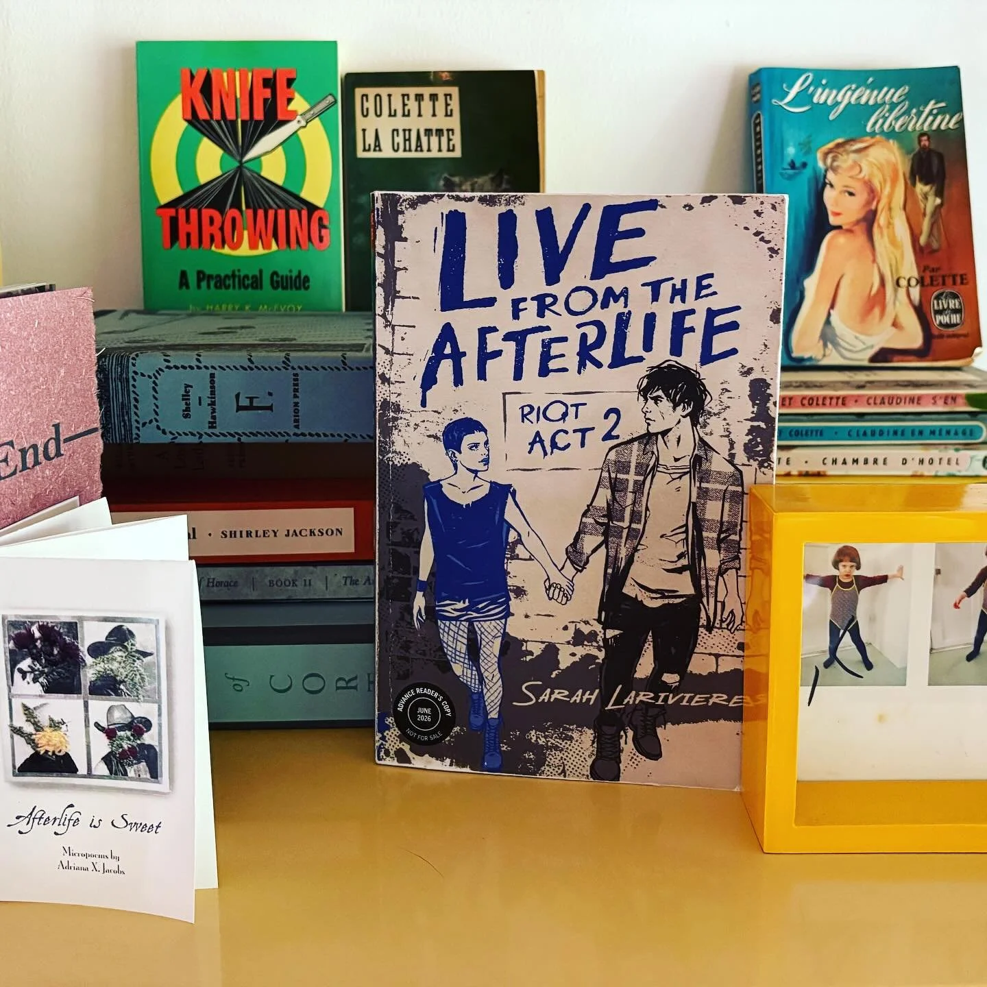 Advance Review Copy of LIVE FROM THE AFTERLIFE on my shelf (with Colette, poems by @axjacobs, and books from my past employer, fine artist book publisher @arionpress).

Pre-order today if you like punk attitude, ghost crushes, and sexy arguments / ha