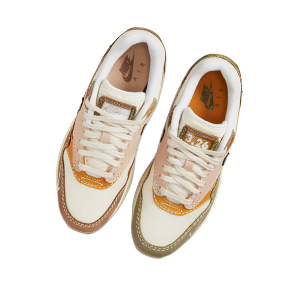 A pair of Nike Air sneakers in beige, white, and orange with white laces and tan soles.