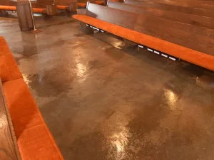 On the above acid-stained concrete floor, you can see three parallel “bands” of coloring that are a slight shade darker brown than the rest of the floor. This is due to shadowing left behind from carpet glue stripper.