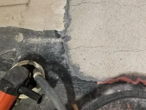There was so much material on the surface of this concrete, including paint, glue, and previously applied cement overlays, that it had to be ground off, leaving exposed aggregate (upper right corner of photo).