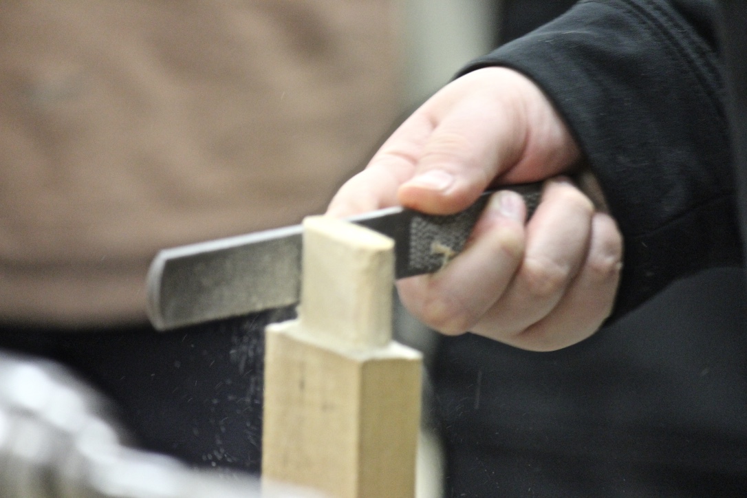 Huslia JHS student files a sled stanchion in Wes Henry's class.