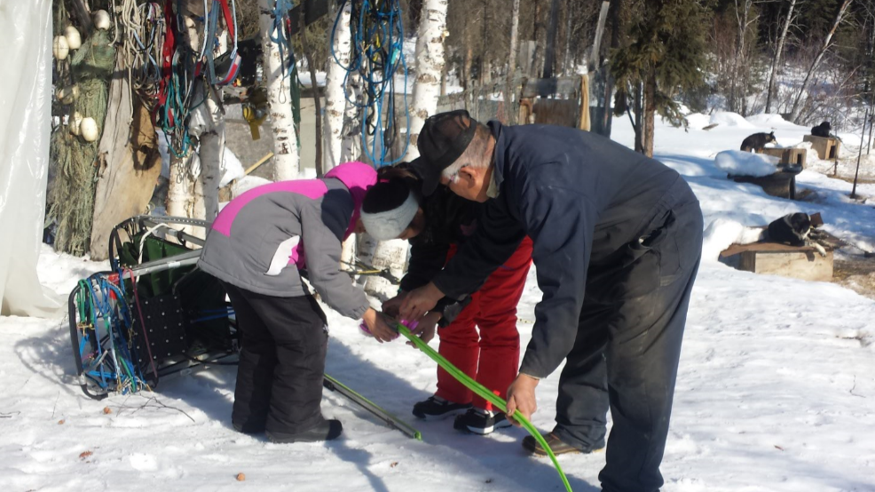 Allakaket School students learn from Musher Steven Bergman how to change sled runner.