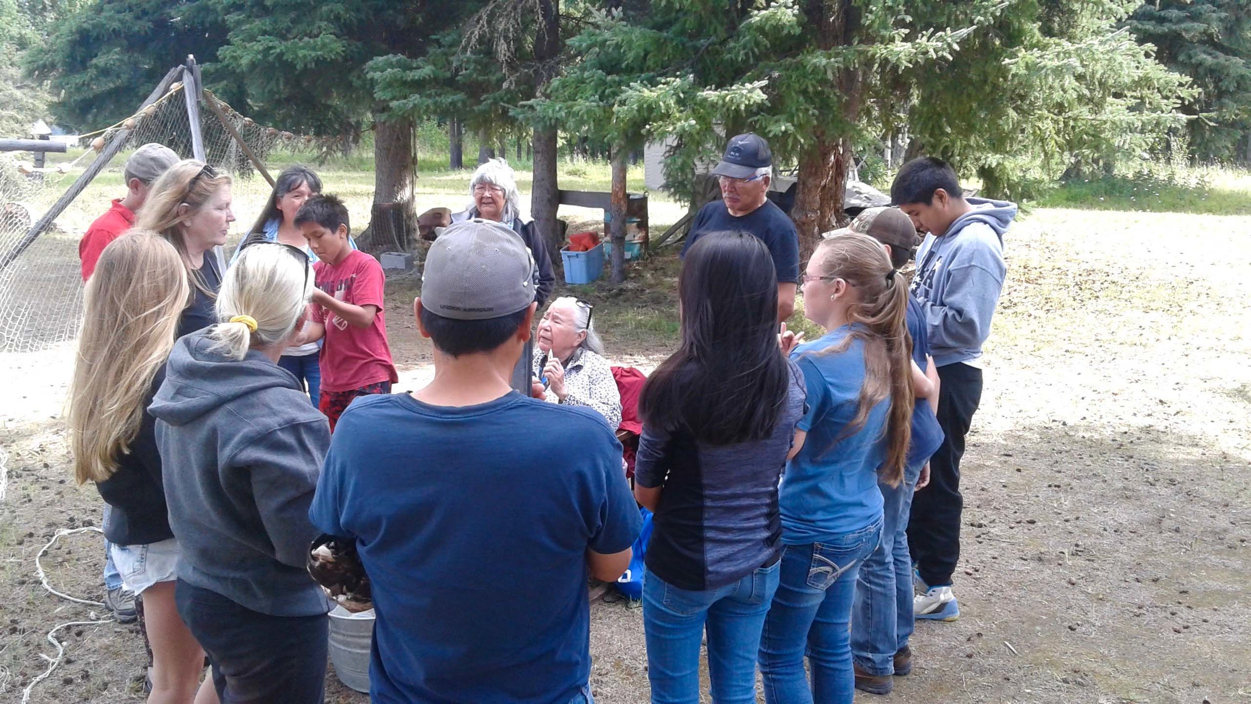 An Elder shows A-CHILL students, dog mushers, and teachers how to mend fish net.