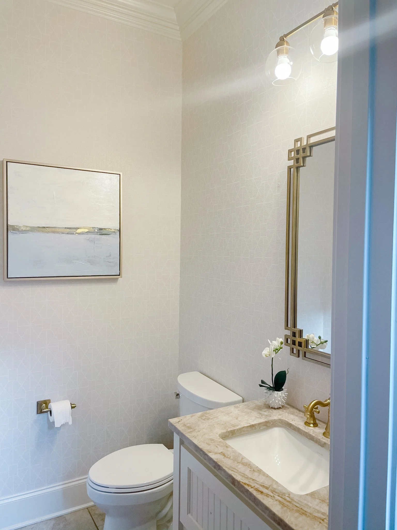 Small framed coastal painting hangs in a bathroom