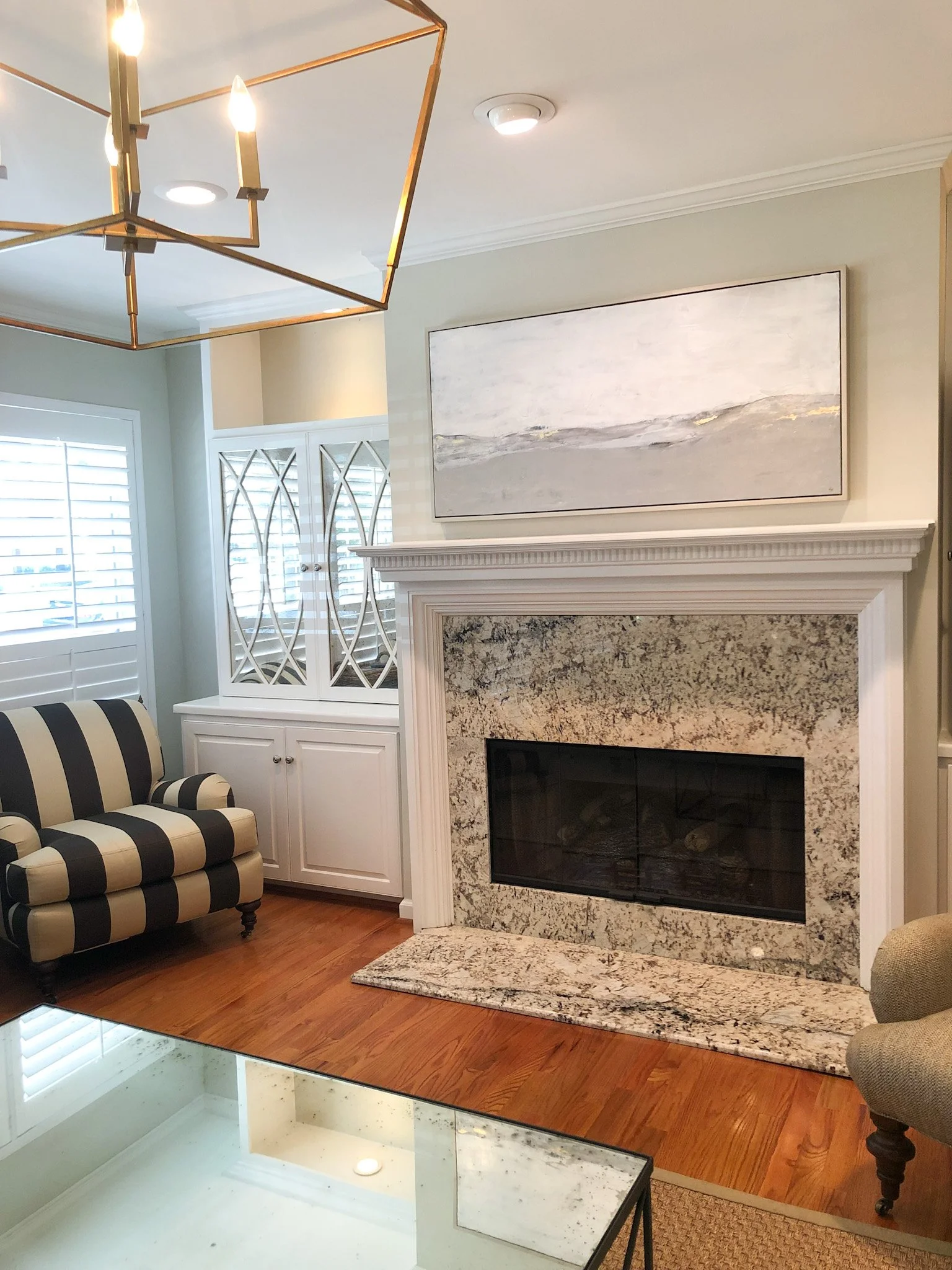 A large abstract original painting hangs over a fireplace in a living room.