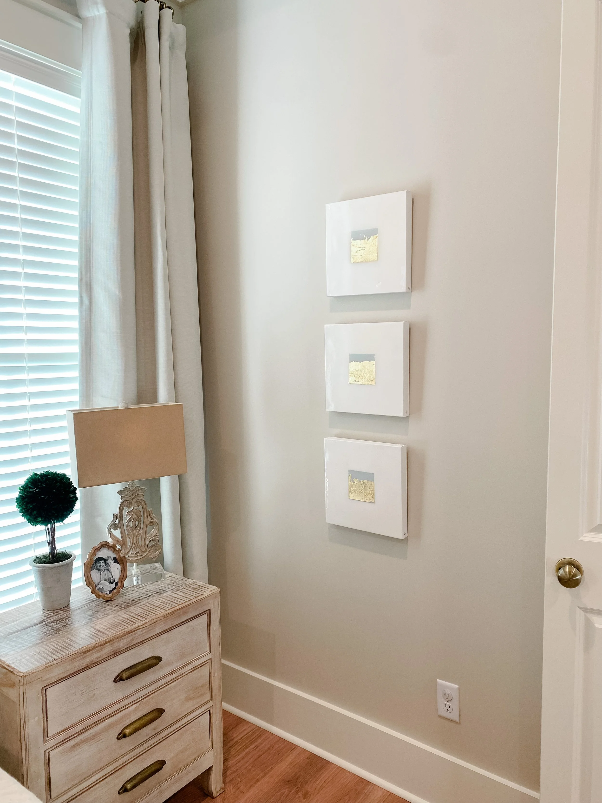Three small famed abstract home decor artwork hangs on a wall.