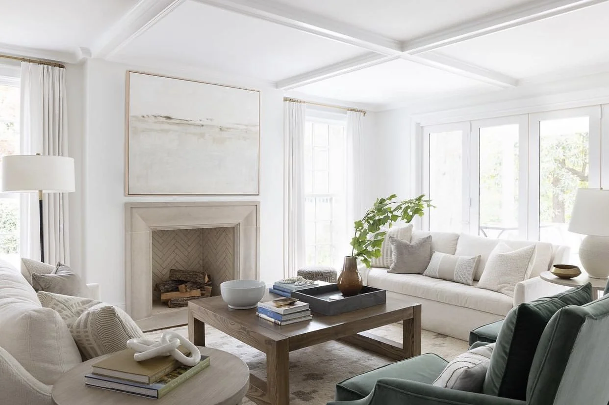 Large muted costal painting hangs in a living room over a fireplace.
