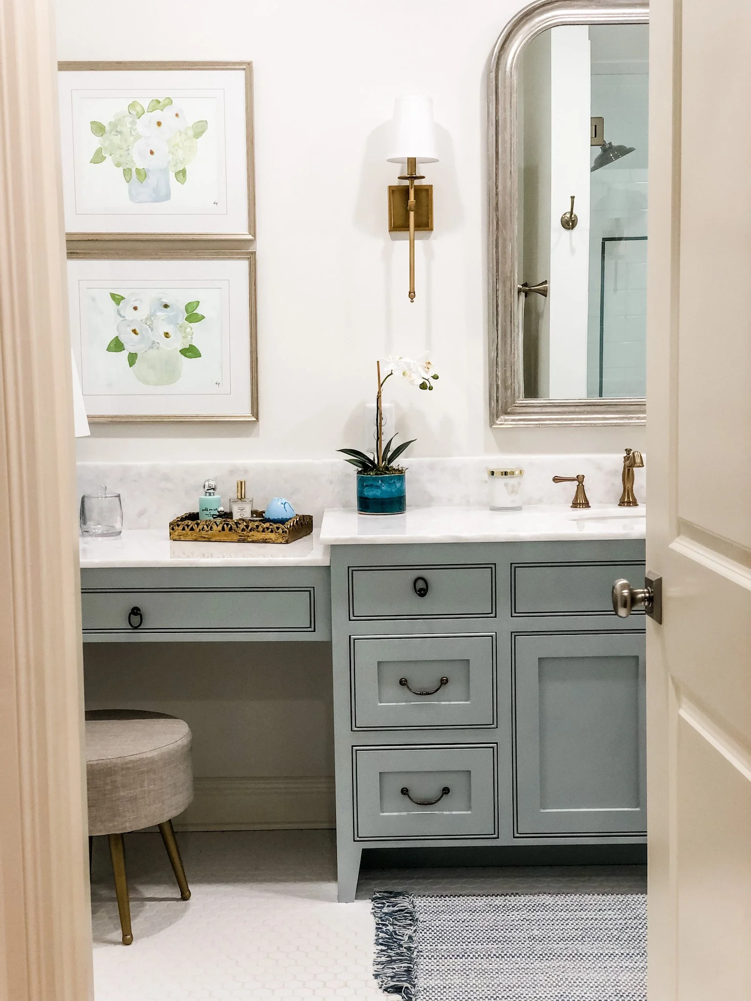 Small framed abstract floral paintings hang in a bathroom over a green sink.