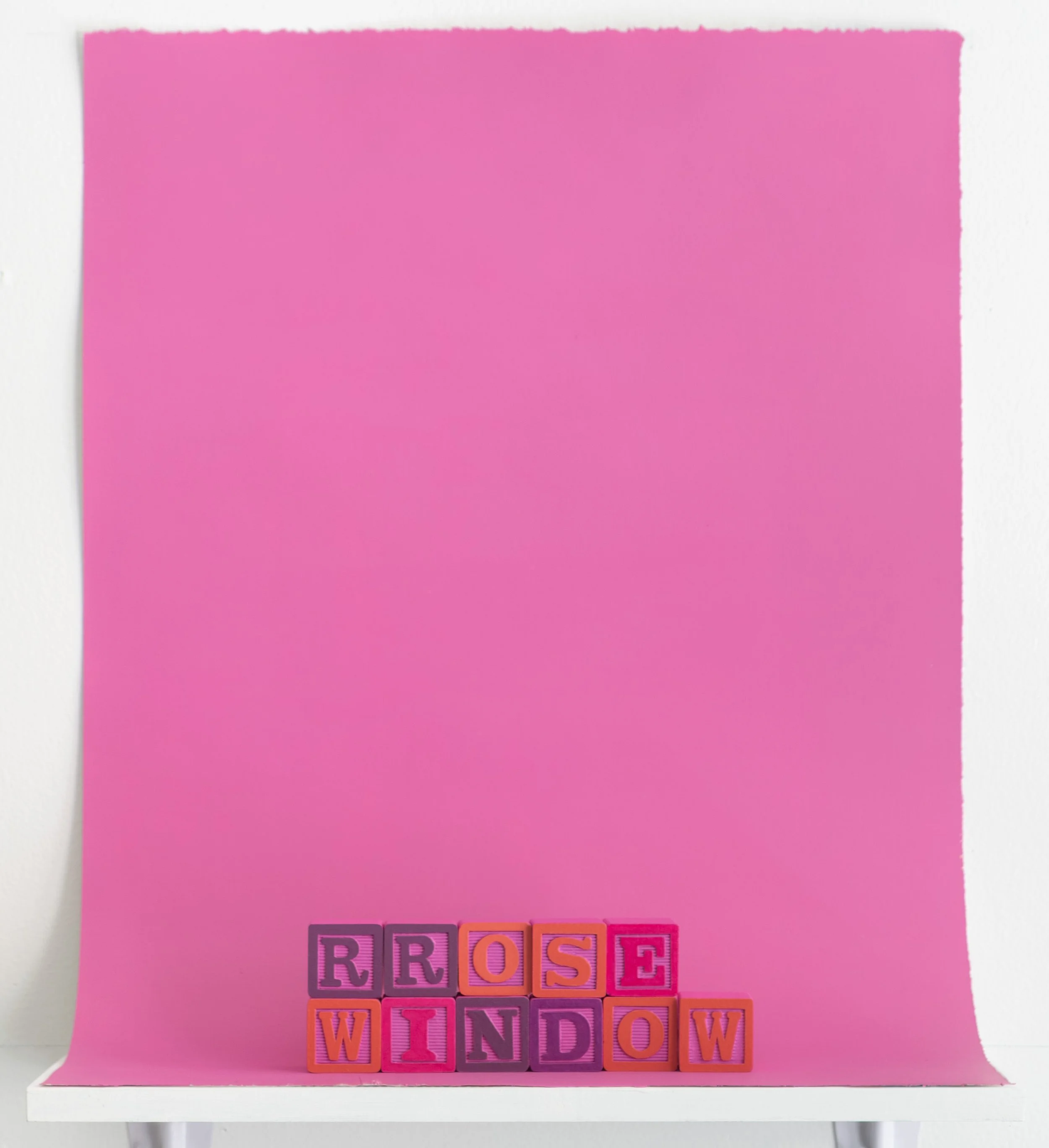 painted alphabet blocks spelling the words “Rrose Window”