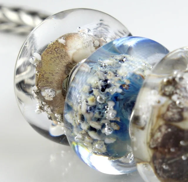 the bubbles are because of reactions inside the glass while it's melting and being wound round the mandrel