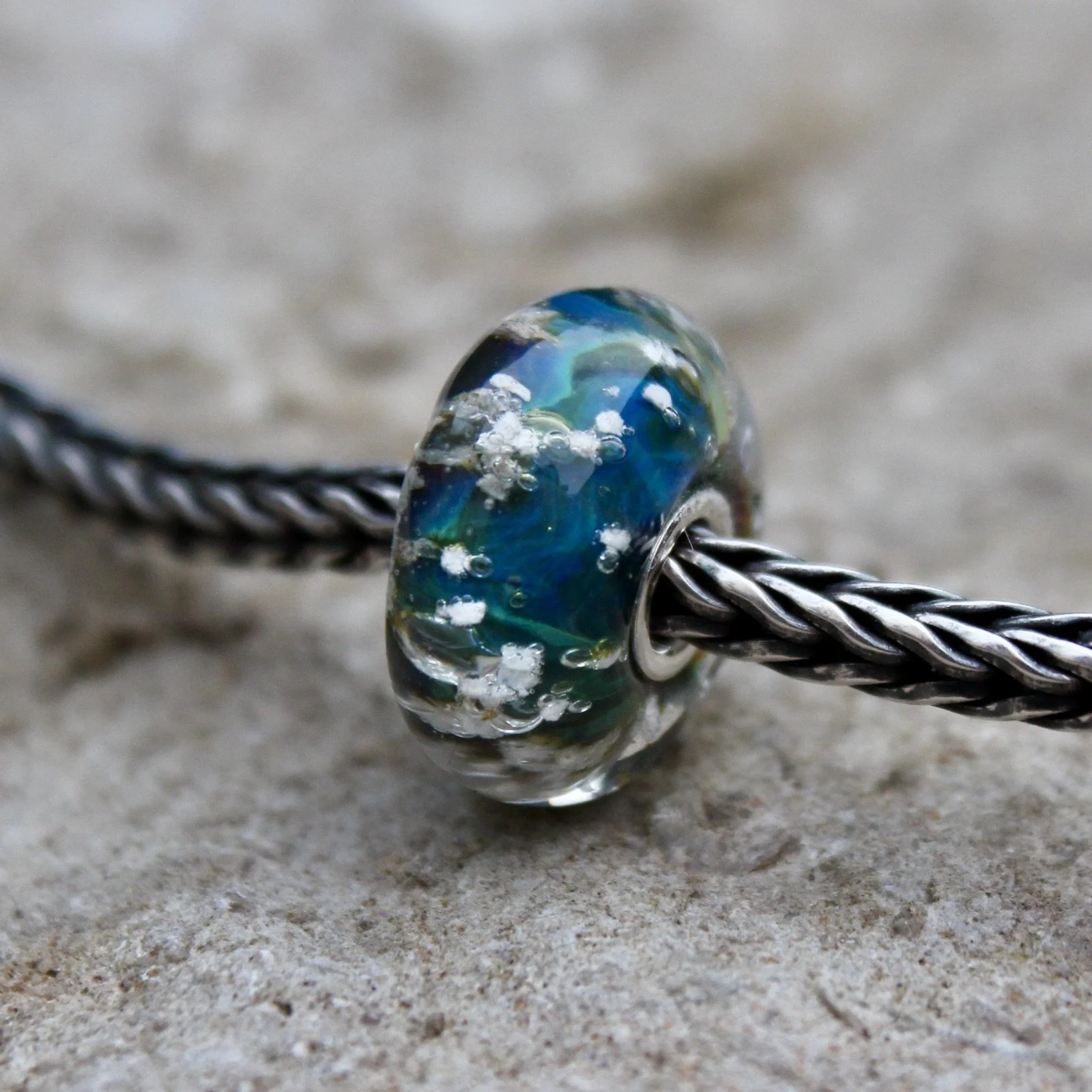 The cremation ash is clearly visible in this rich blue green charm bead