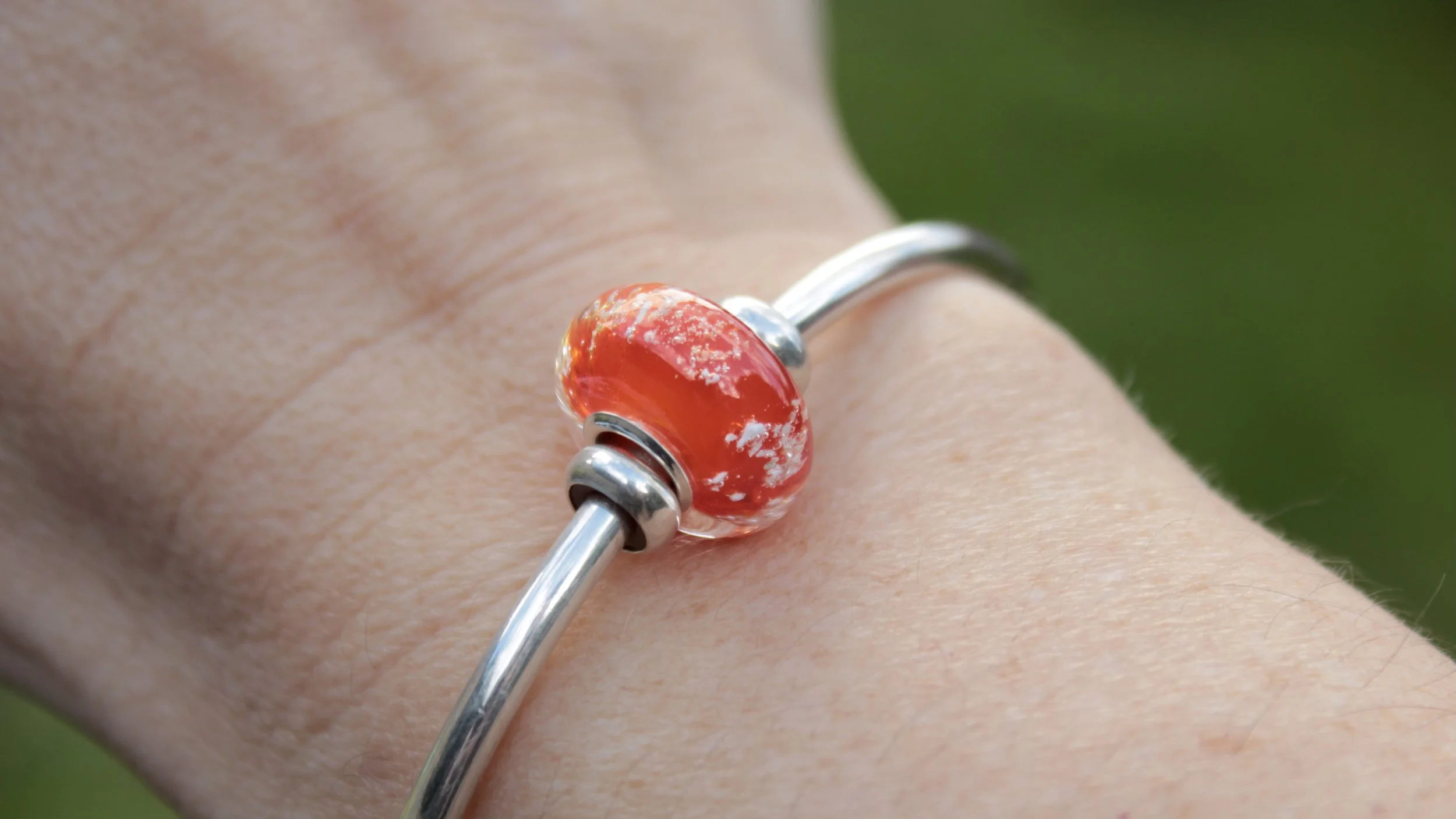 Single charm bead worn on a simple Meadowhawk cuff bracelet