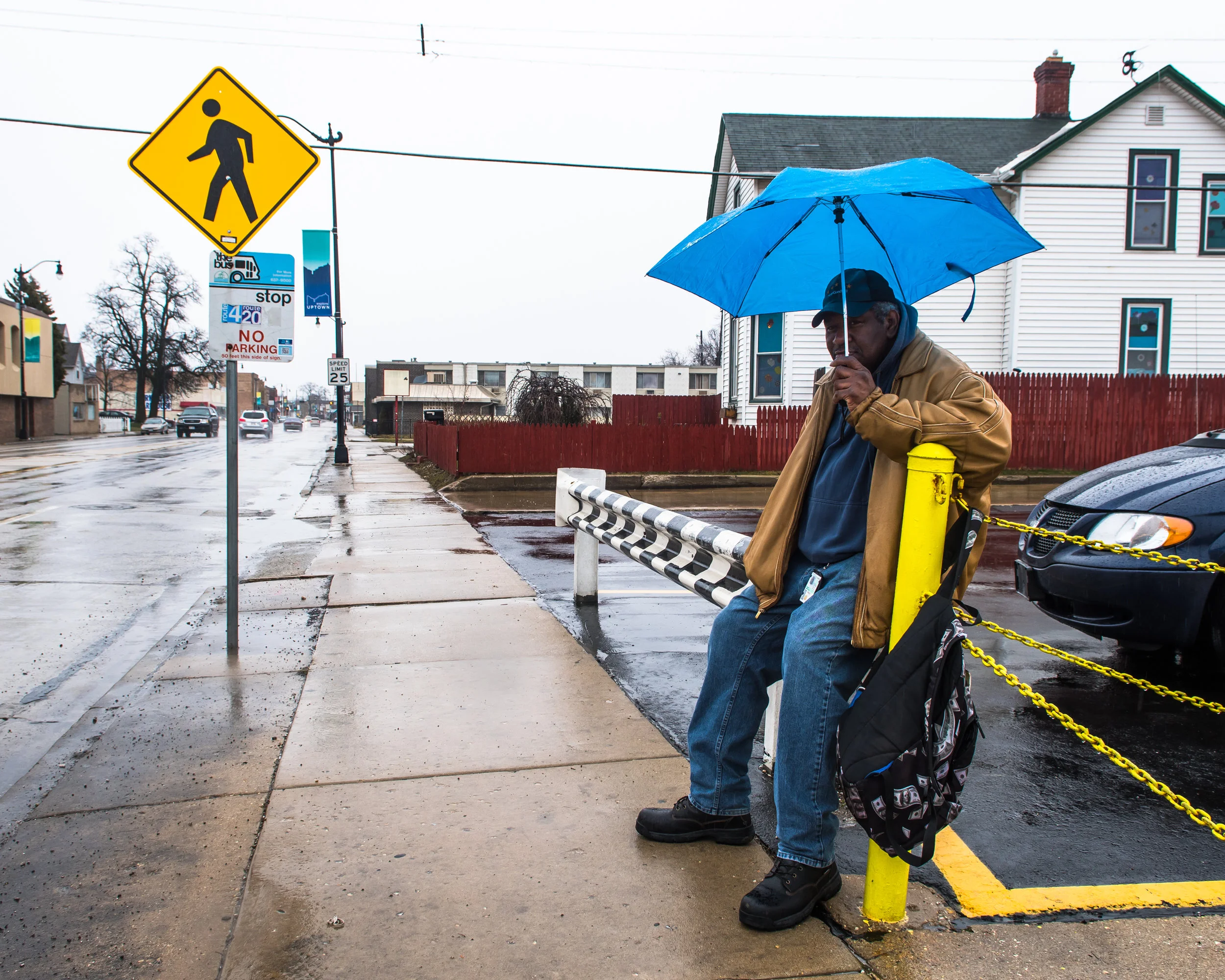 On his daily commute Jimmy Canady patiently waits for the No. 4 bus with his umbrella. 