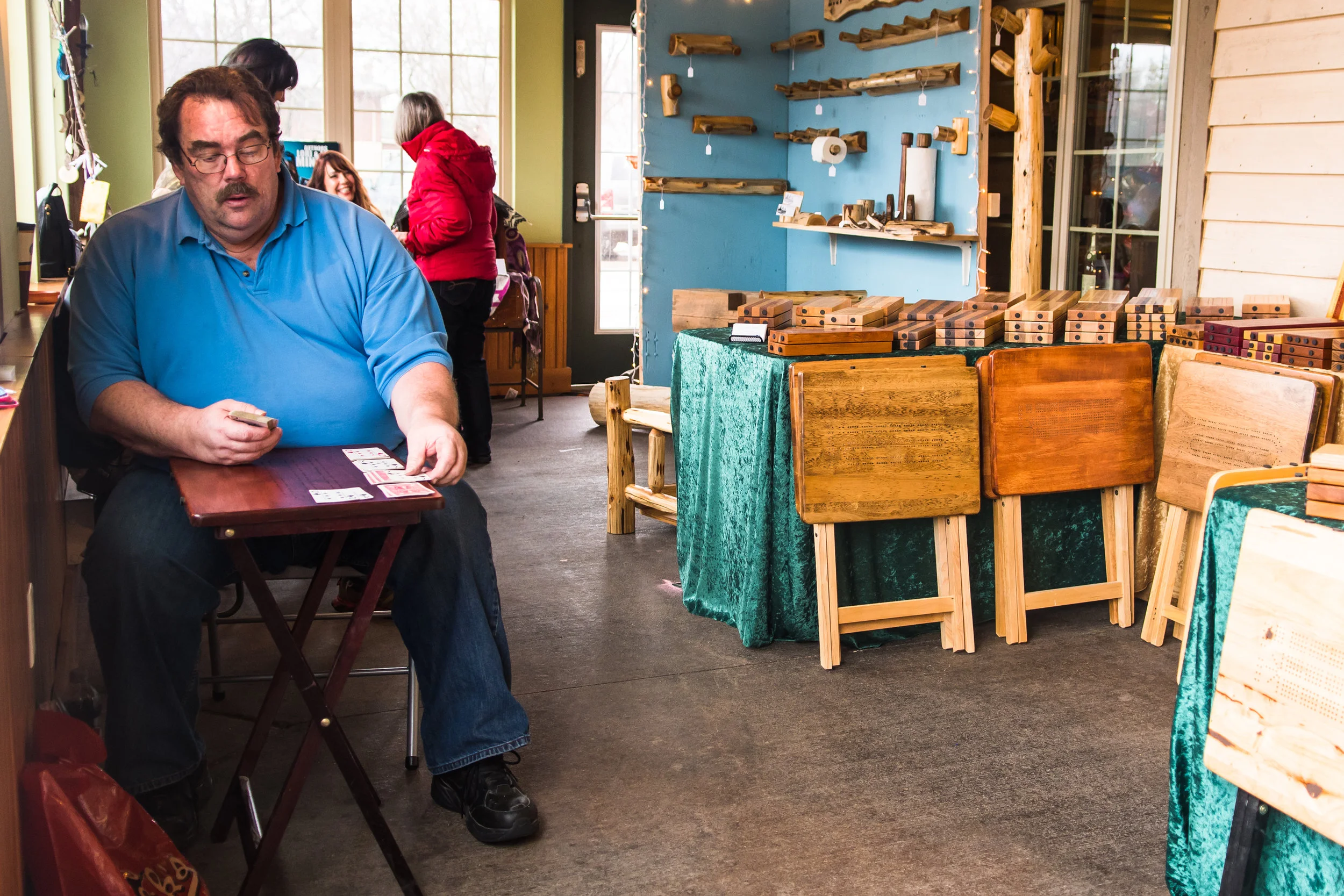 Jim Thompson plays solitaire in front of his booth displaying his custom cribbage and other game tables at the Borzynski's Farm and Floral Market Spring Arts & Craft Fair on Sunday.