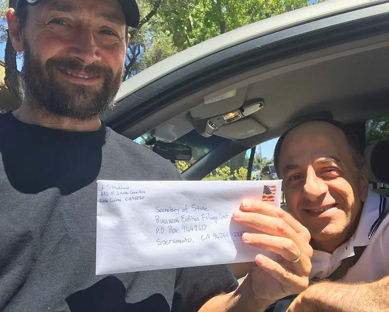 Nick holding up an envelope containing the registration of the foundation with the State of California prior to mailing it.