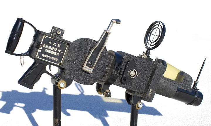 Rokuoh-Sha Type 89 35mm half-frame movie camera. Large crank on the right side winds a spring that advances the film when fired. WWII vintage. There was originally a watch under the yellow plastic shroud on the front of the camera. Through a split-prism assembly, the watch was filmed at the same time as the target, allowing the viewer to determine the duration of fire. Konishoruko Mfg. Co. lens; later to become Konica.