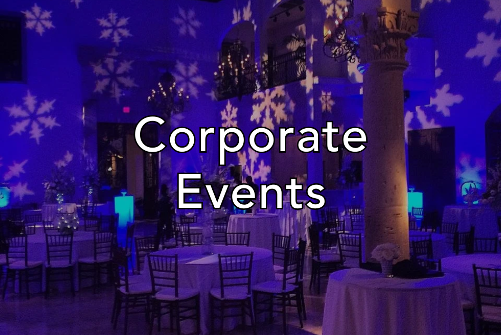 Elegant event space decorated with blue lighting, snowflake projections, and round tables with white tablecloths and floral centerpieces, suitable for corporate events.