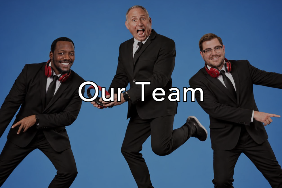 Three men in suits and red headphones playfully jumping against a blue background, with center man holding a trophy, and the words "Our Team" overlaid on the image.