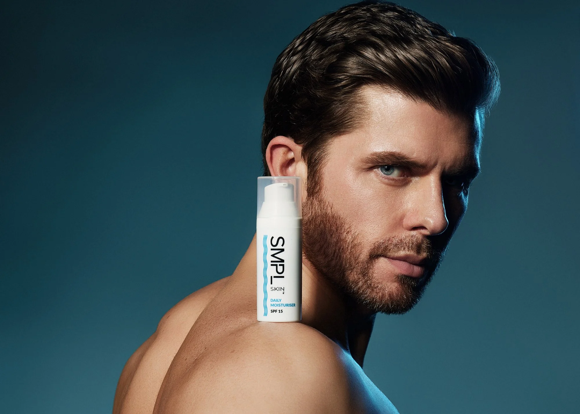 A commercial photography of a portrait of a handsome man with a face cream on his shoulder.
