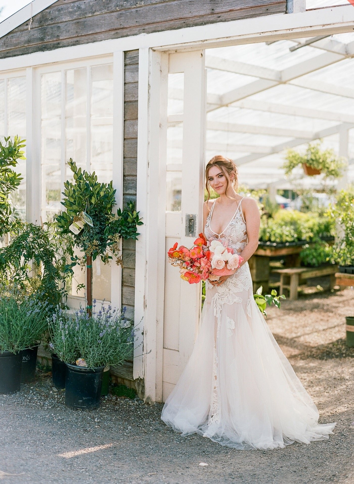 Bride poses at the entrance to Christianson's Nursery with a colorful and modern bouquet