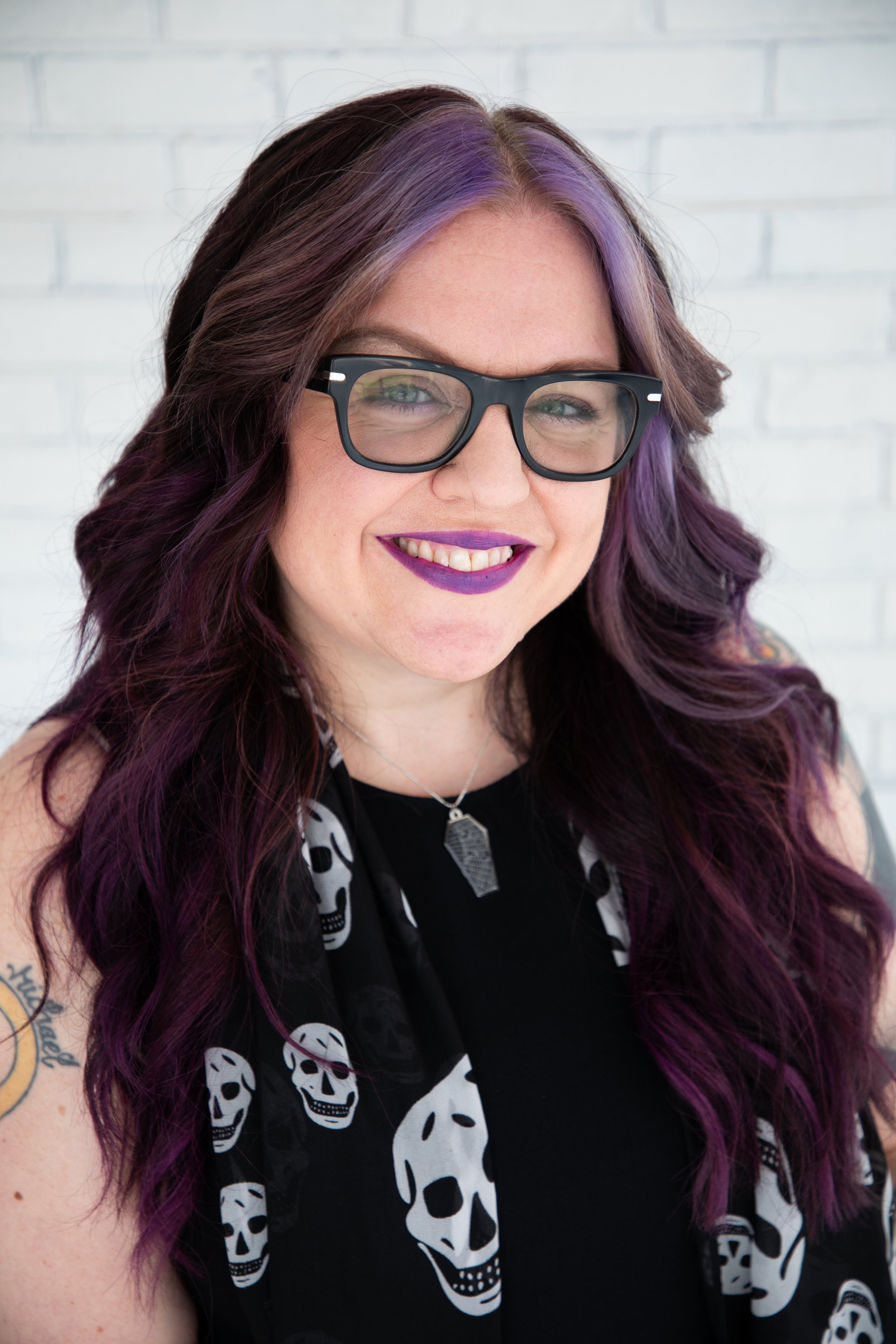 nicole-wight-product-marketing-executive purple hair glasses purple lipstick white woman skull scarf