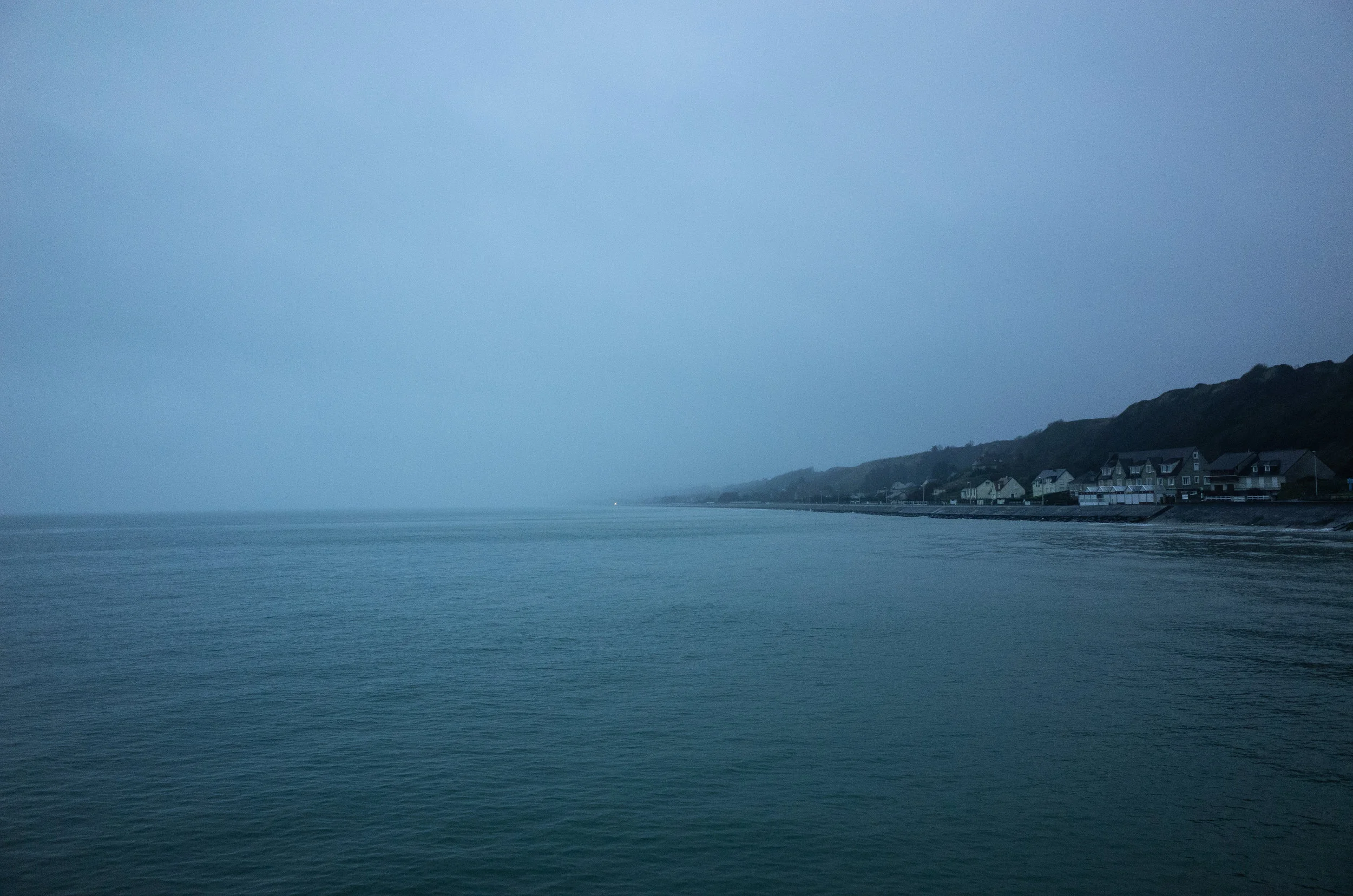 Omaha Beach, coastline: As seen from the observation pier at daybreak. The locals have largely reclaimed the beach as evidenced by the houses built just beyond the current sea wall.