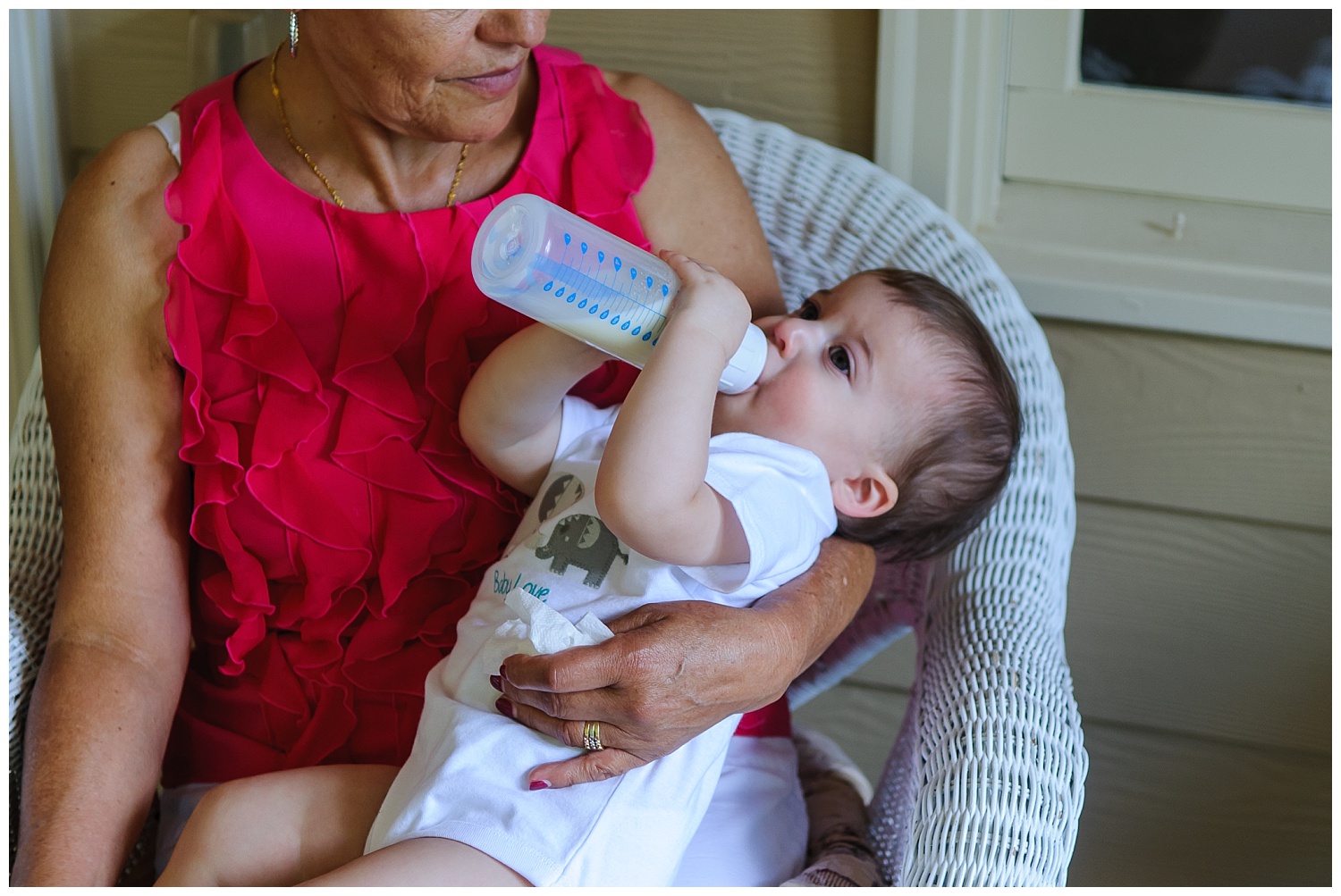 this is an image of the child drinking a bottle and being held by his grandmother. the image was taken at the child's first birthday party in marietta, georgia.
