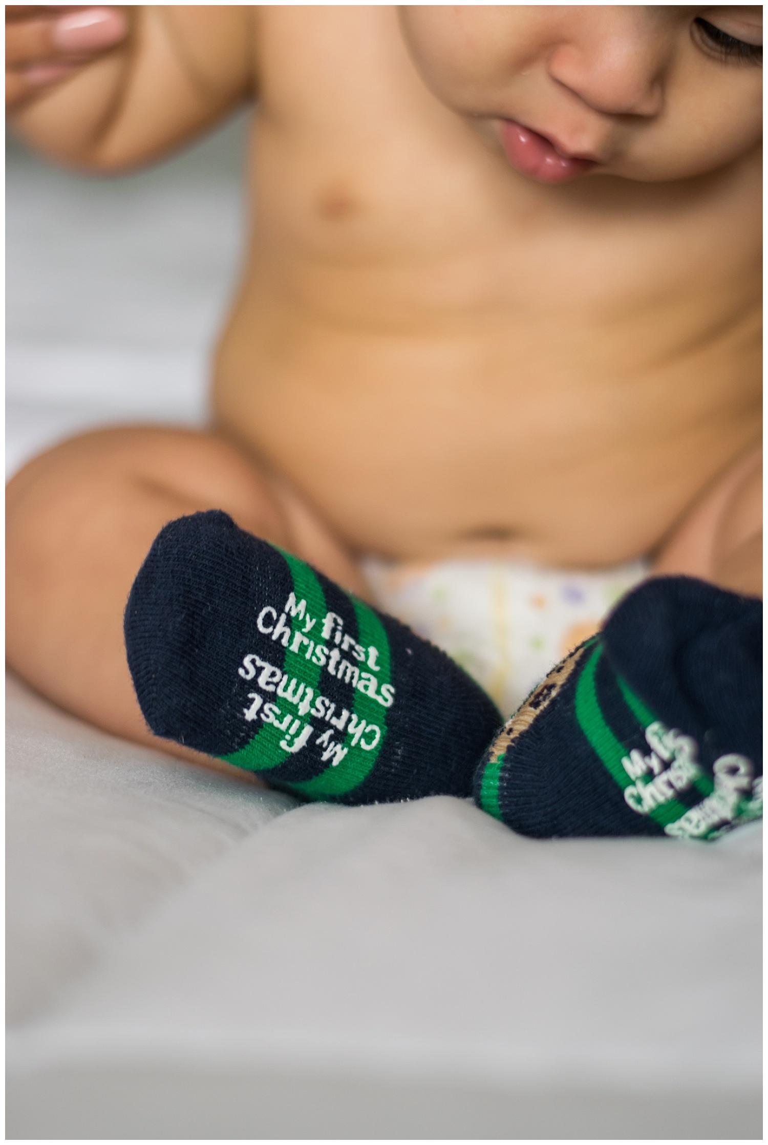 this is a closeup image of a baby boy looking at his "first christmas" socks during an in home lifestyle session in marietta georgia