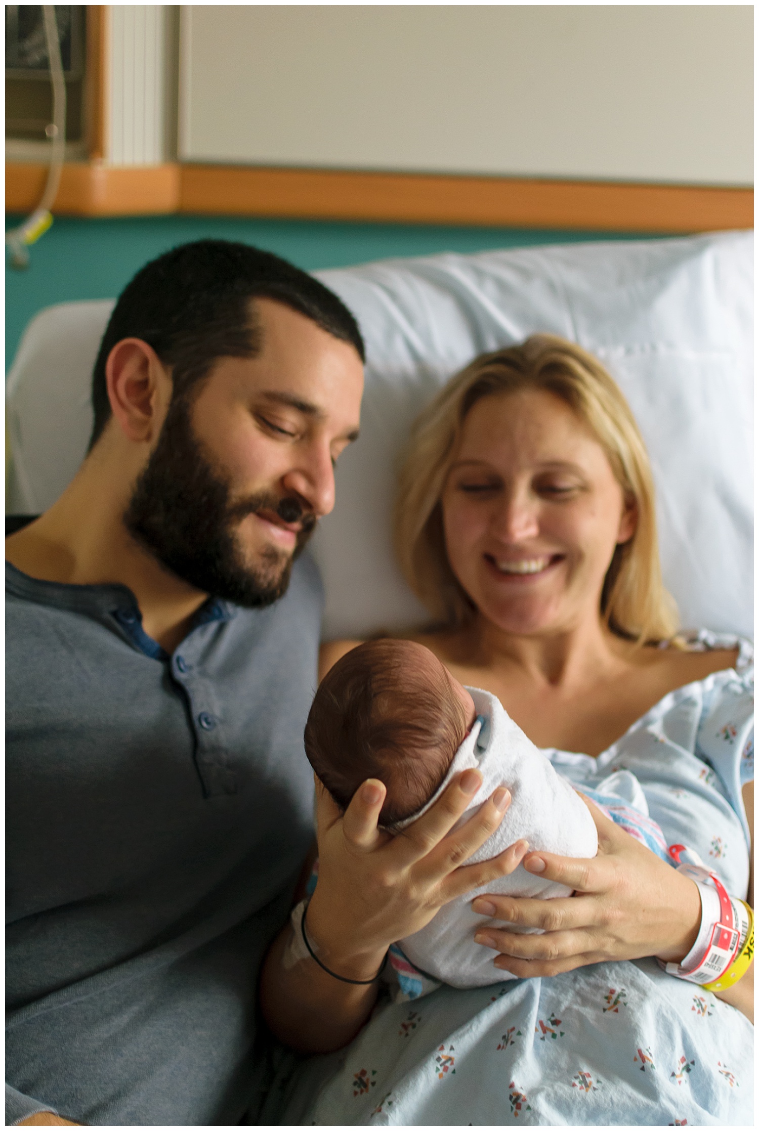 this is an image taken at piedmont hospital during a fresh 48 newborn session. mom and dad are holding the baby girl and smiling and looking at her.