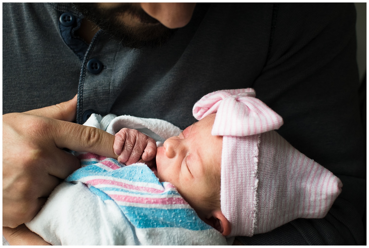 this is an image of a newborn baby girl, one day old, holding onto dad's finger. the image was taken during a fresh 48 session in atlanta georgia at piedmont hospital.