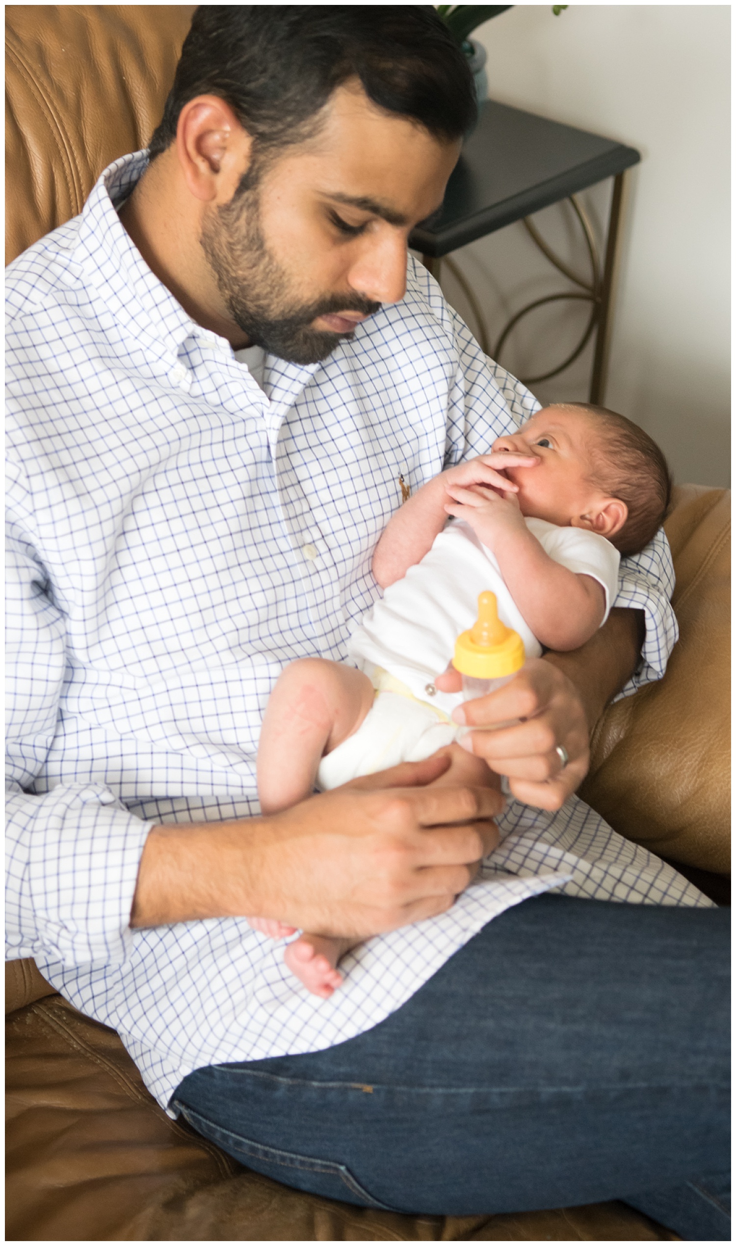this is a candid image of a dad holding his newborn son while sitting on the couch. this was taken during a lifestyle newborn family session in decatur georgia.