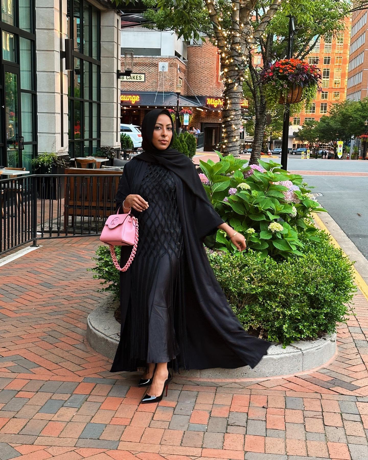 @nada.ozz in a classy black abaya with a cage dress and a pink pop of color 