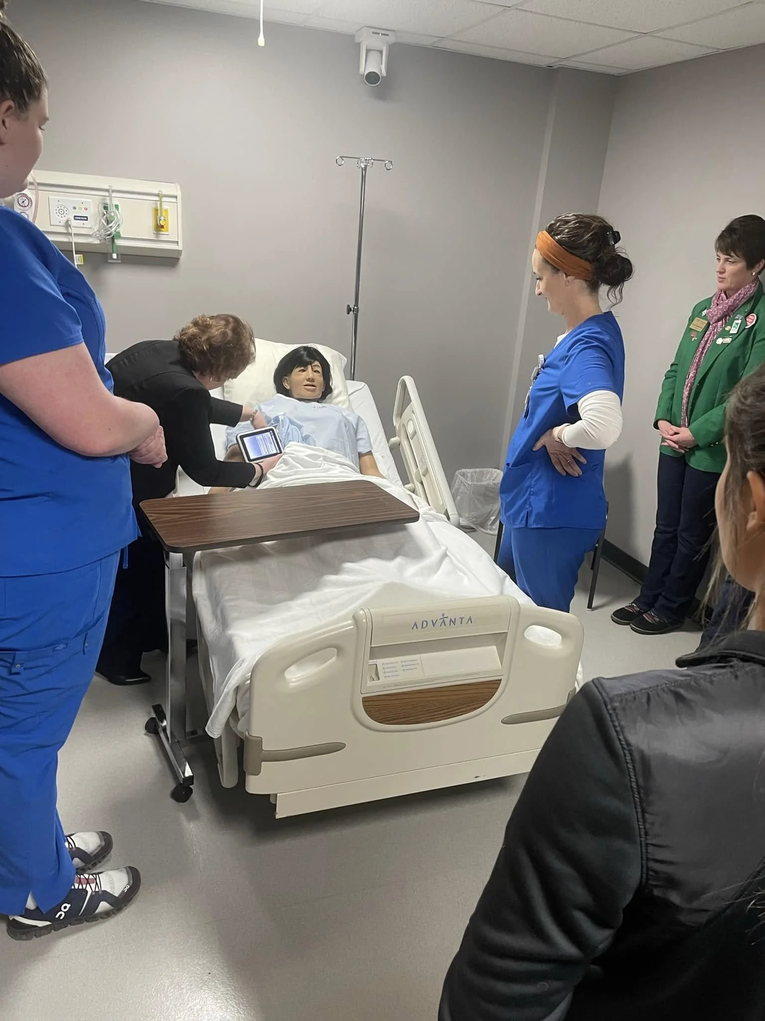 A young woman in a hospital bed being attended by nurses and medical staff in a hospital room.