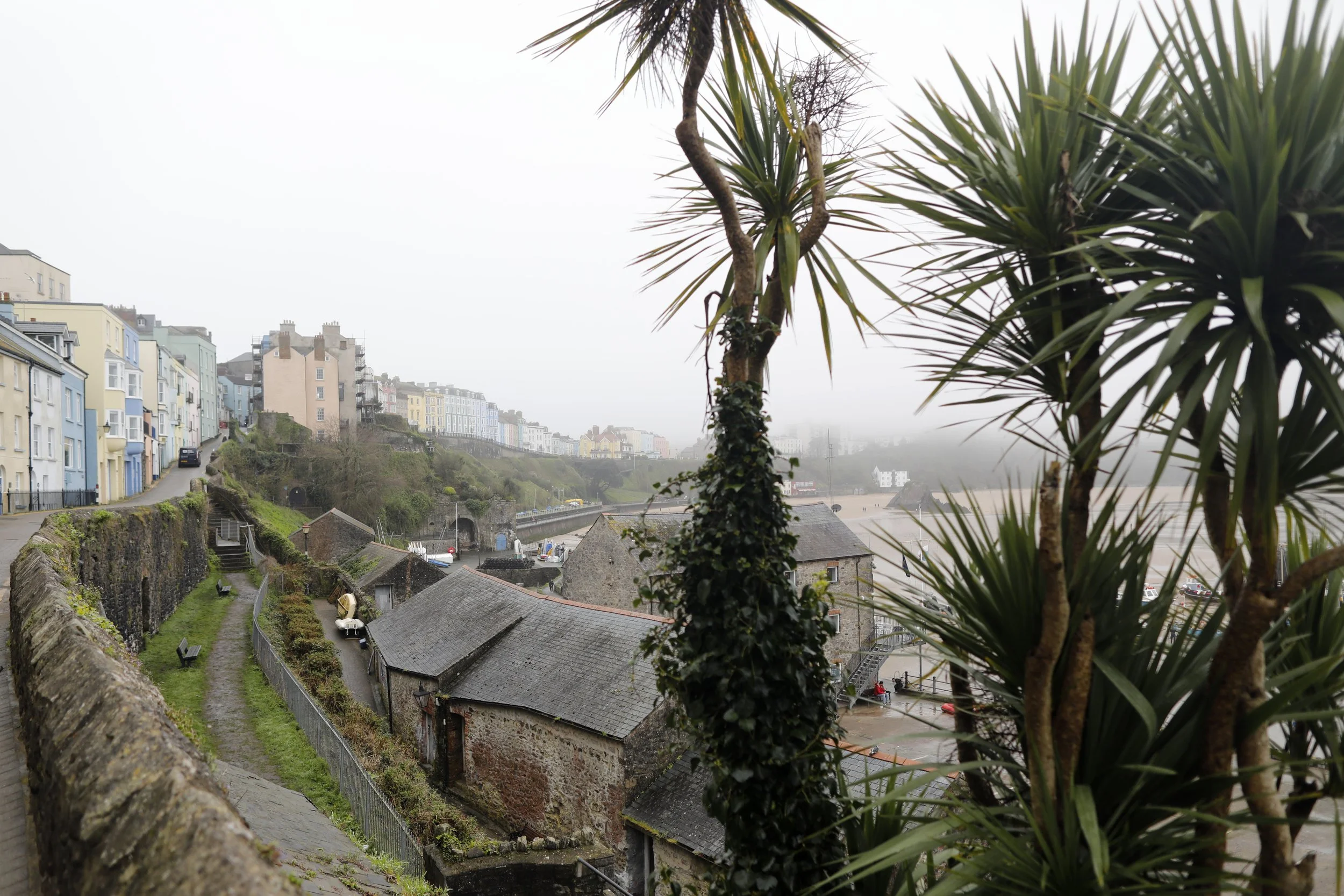 View of main street in Tenby, colorful housing along the street overlooking the beach on a foggy morning