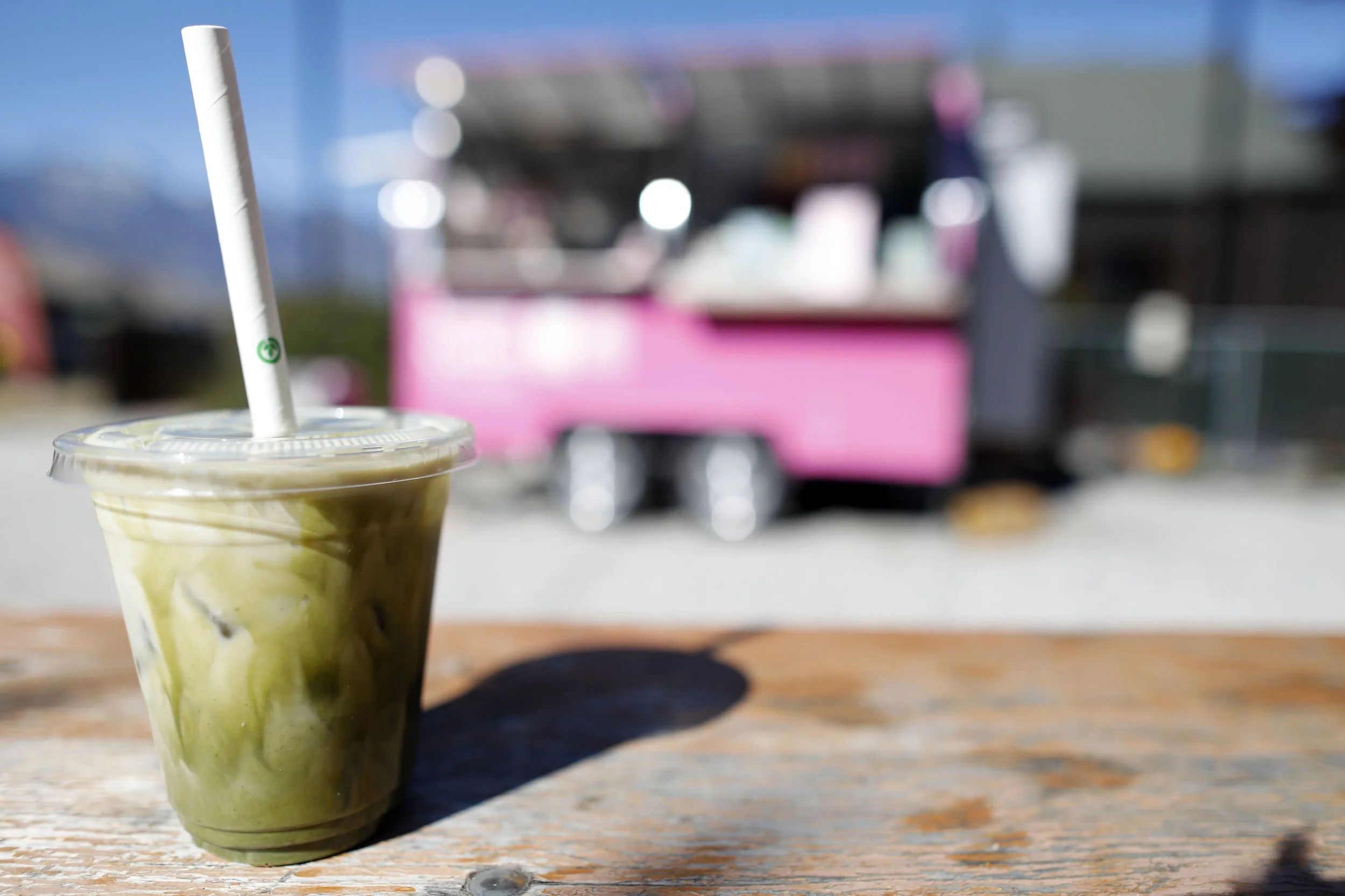 Matcha latte on a wood table with pink coffee trunk in background