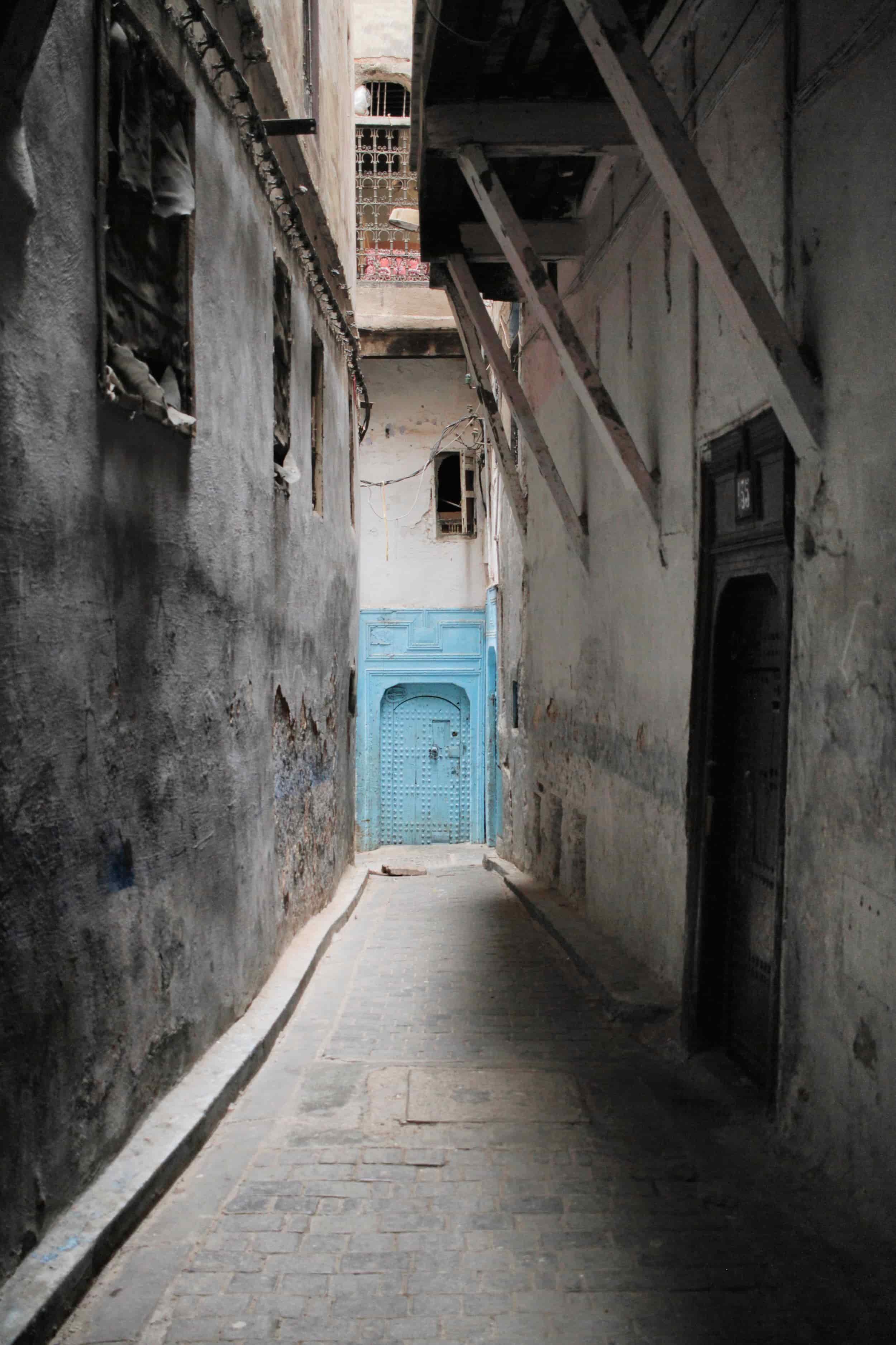 Dusty alleyway with blue door at end, Fes, Morocco