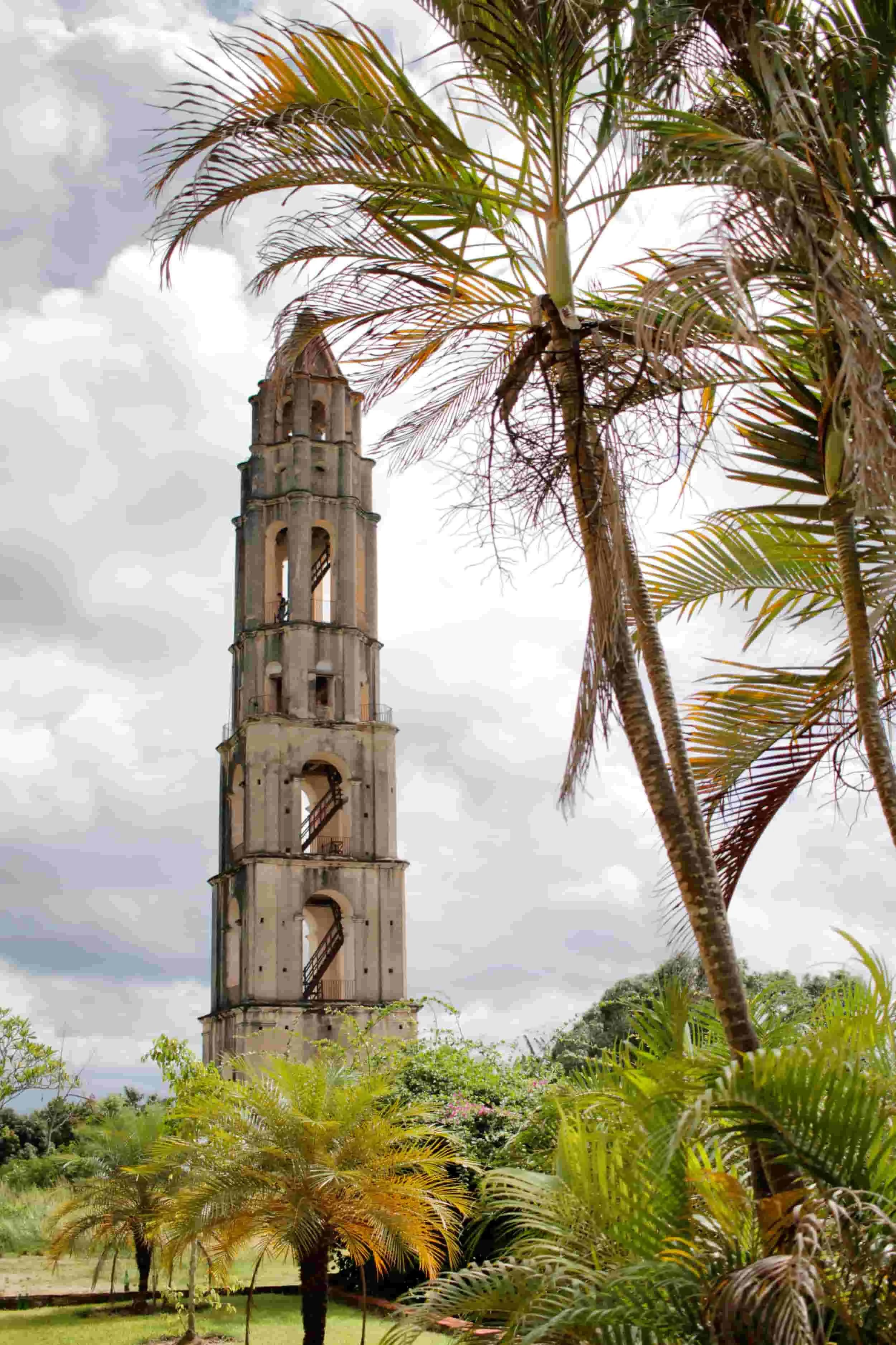 Tall stone tower beyond palm trees in Trinidad, Cuba