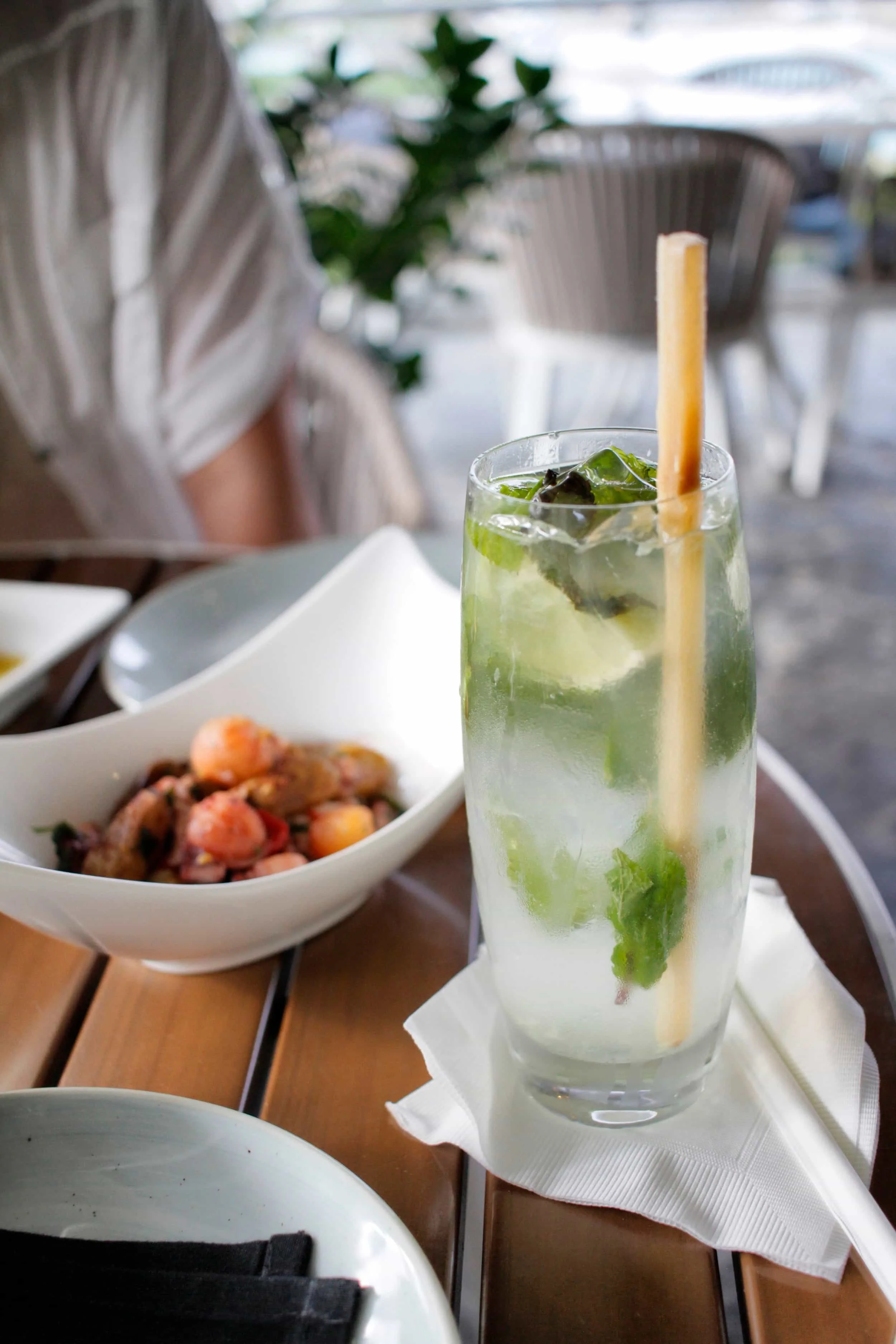 Tall glass with a mojito and dish of food