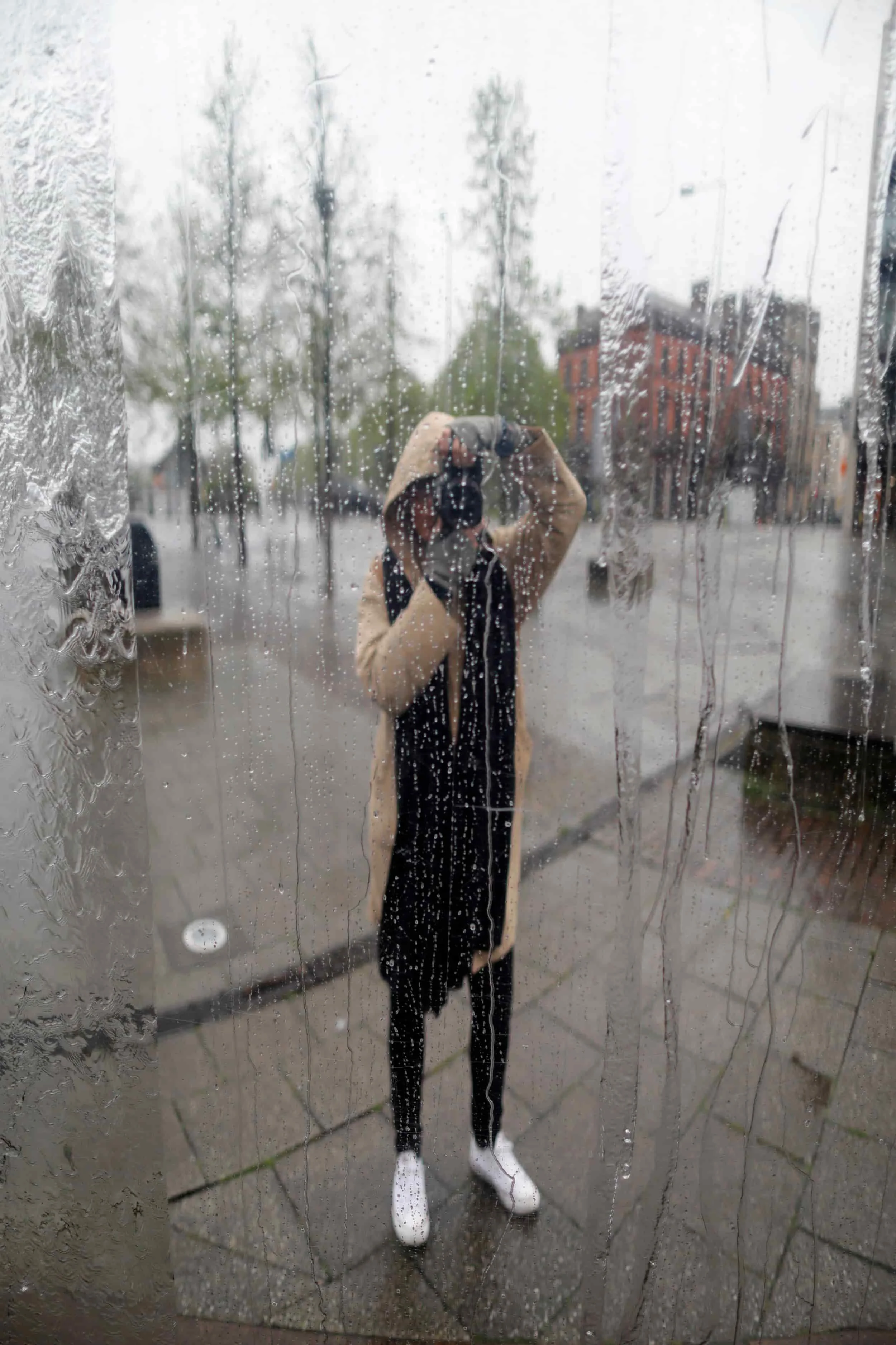 Girl in rainy reflection taking her own photo, city center in Cardiff Wales