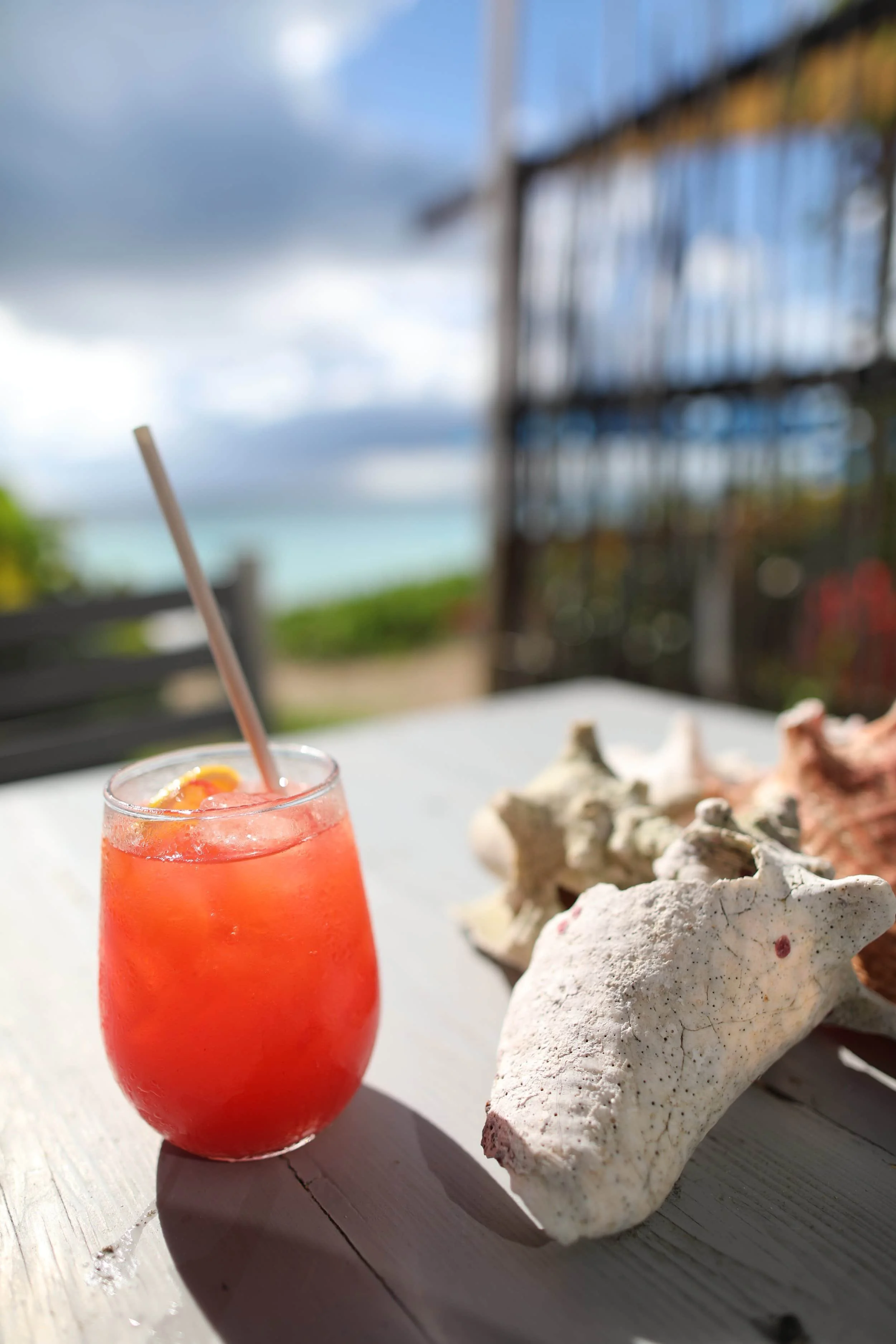 Red juice in a glass with straw on beachside table on Antigua island
