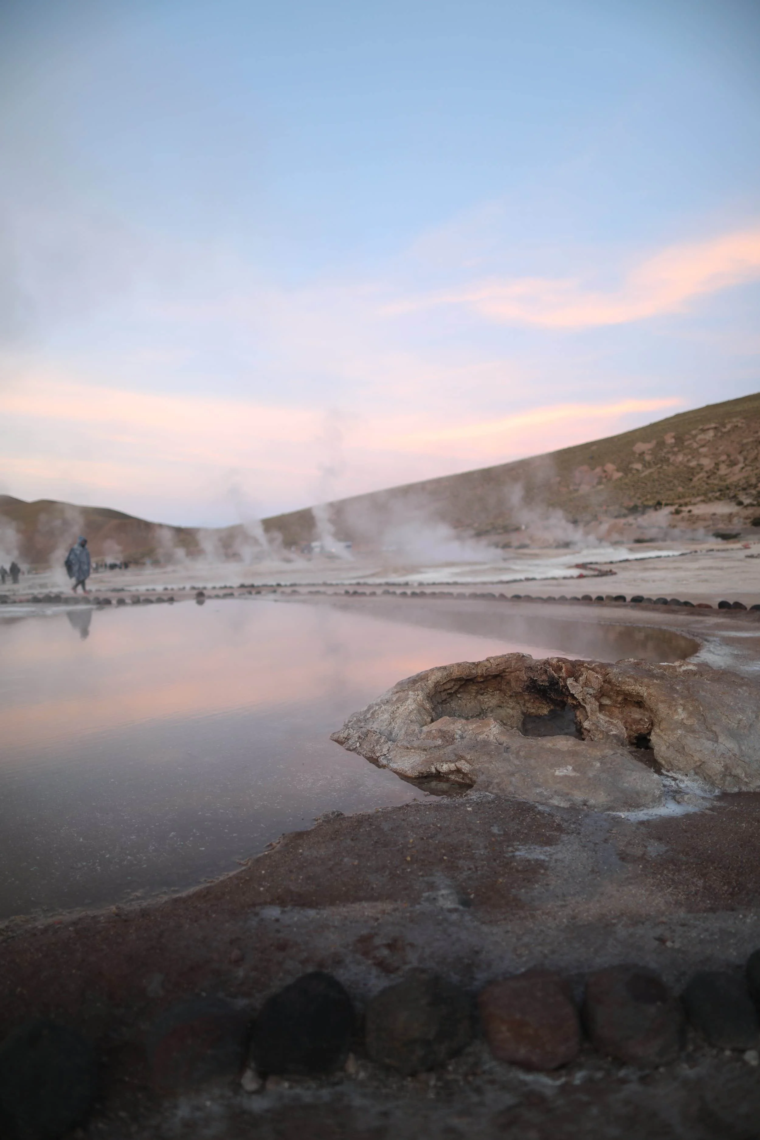 Golden morning sunlight illuminating clouds of steam at El Tatio Geysers near San Pedro de Atacama, Chile.