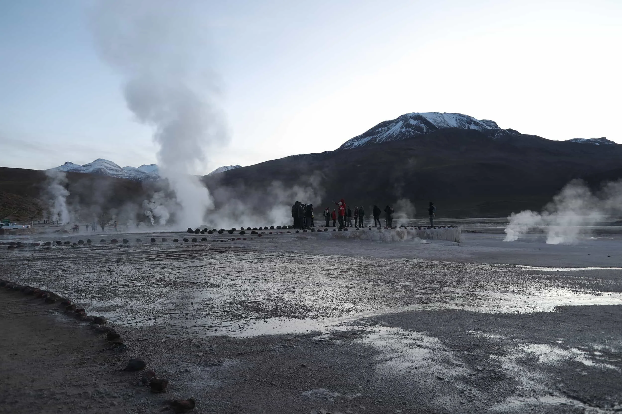Steam rising from the El Tatio Geysers at sunrise, surrounded by the dramatic volcanic landscape of the Atacama Desert in northern Chile.