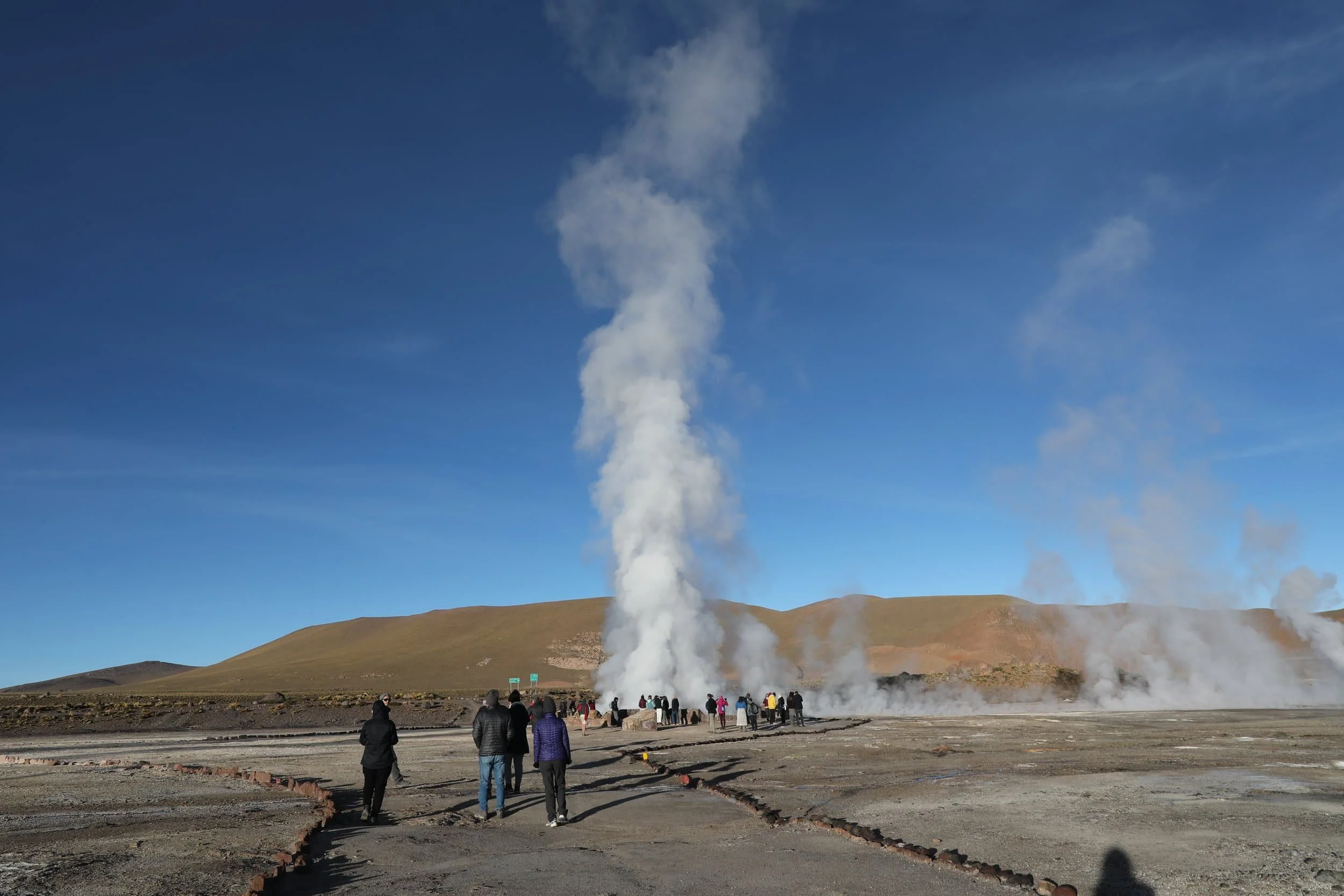 Powerful steam rising from the Assassin Geyser, surrounded by dark mineral formations at El Tatio in Chile.