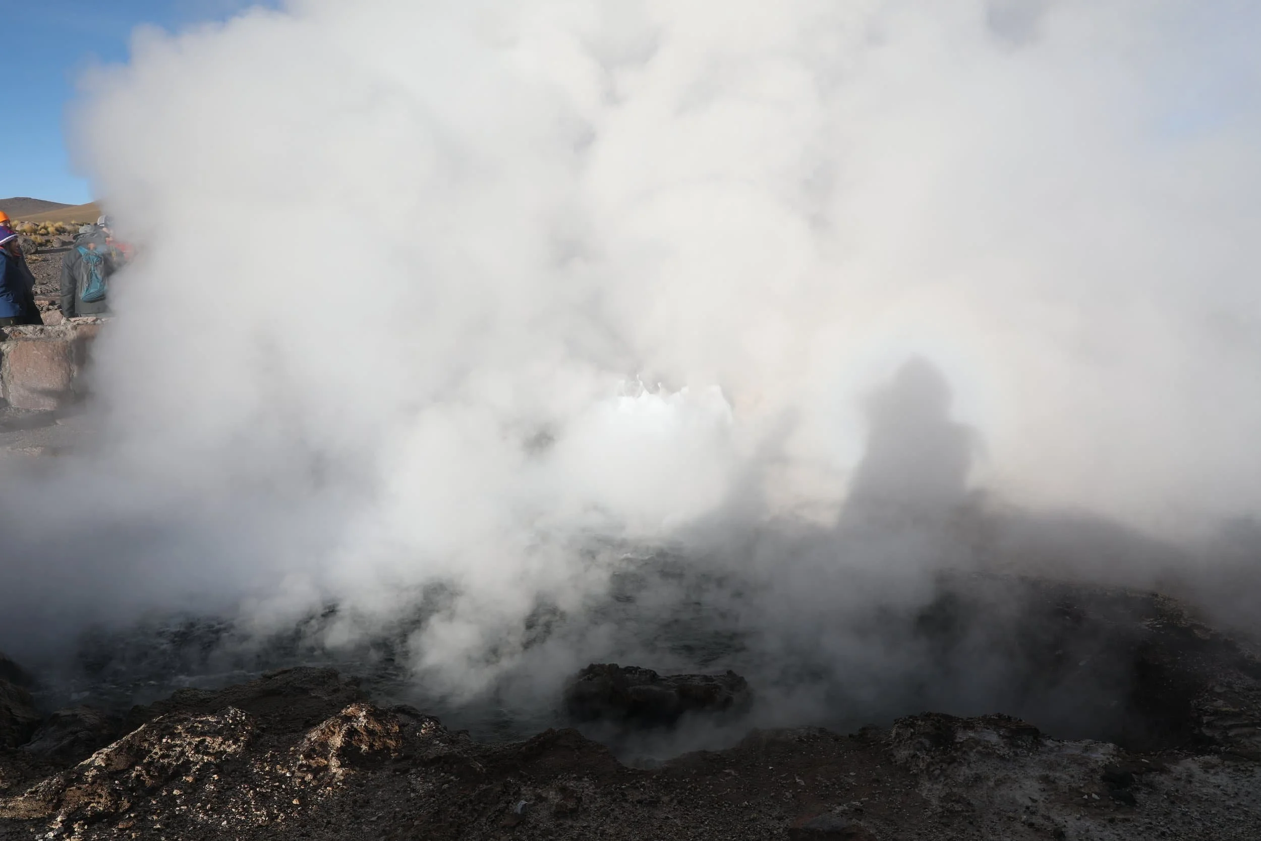 Powerful steam rising from the Assassin Geyser, surrounded by dark mineral formations at El Tatio in Chile.