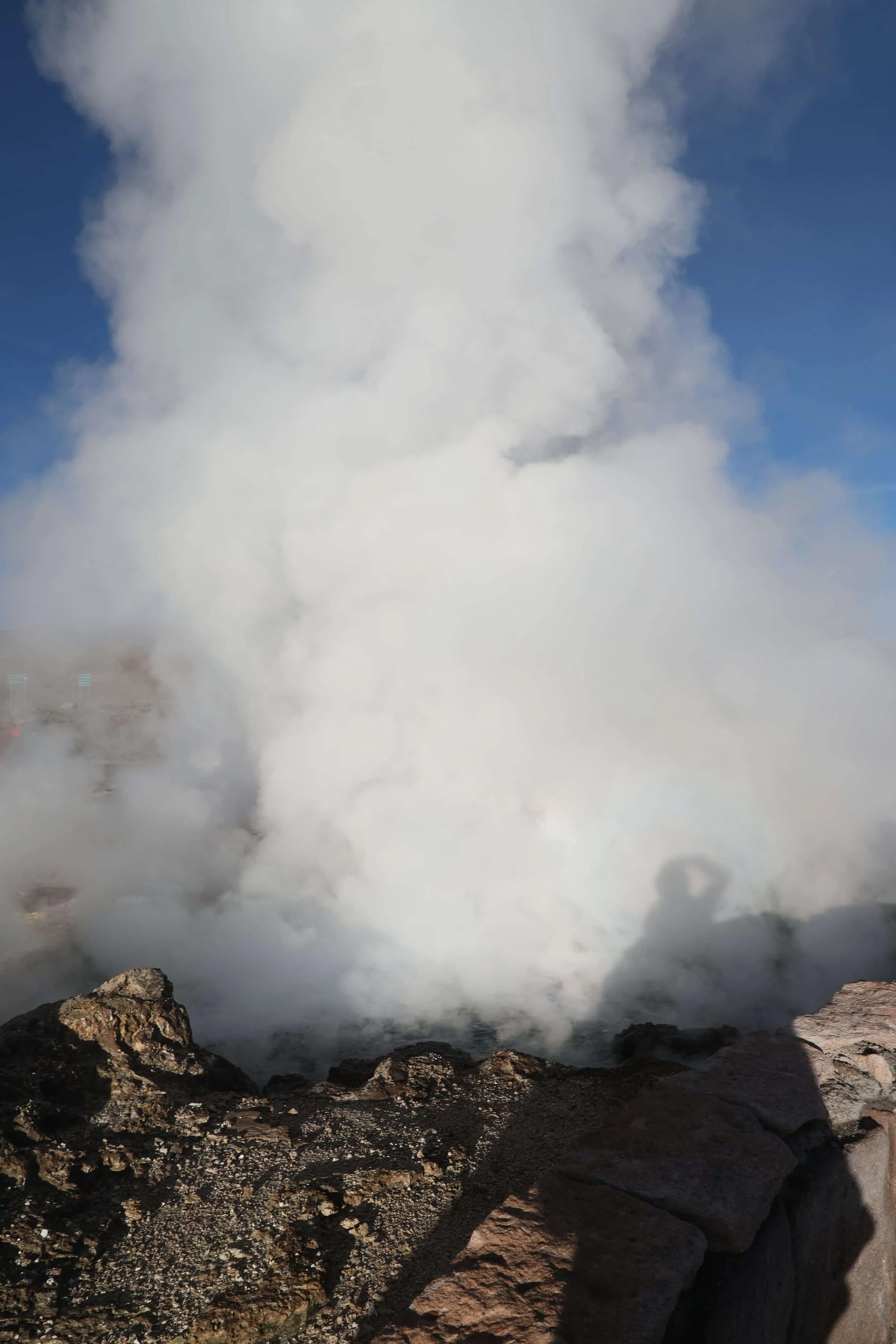 Powerful steam rising from the Assassin Geyser, surrounded by dark mineral formations at El Tatio in Chile.