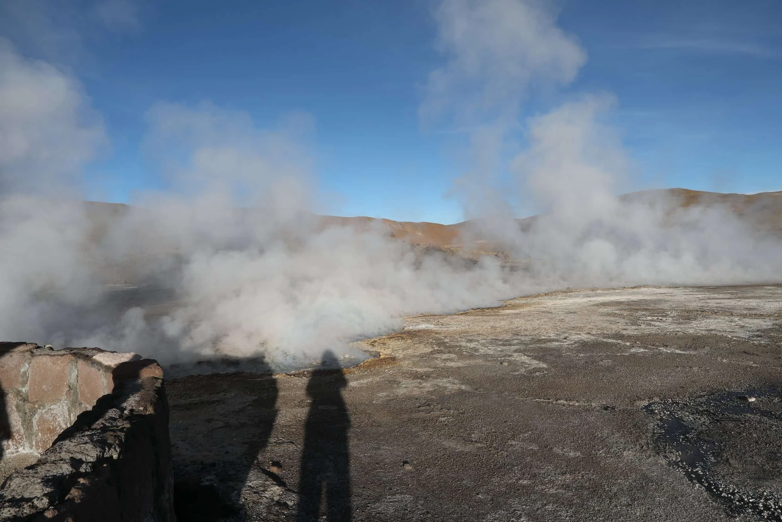Powerful steam rising from the Assassin Geyser, surrounded by dark mineral formations at El Tatio in Chile.