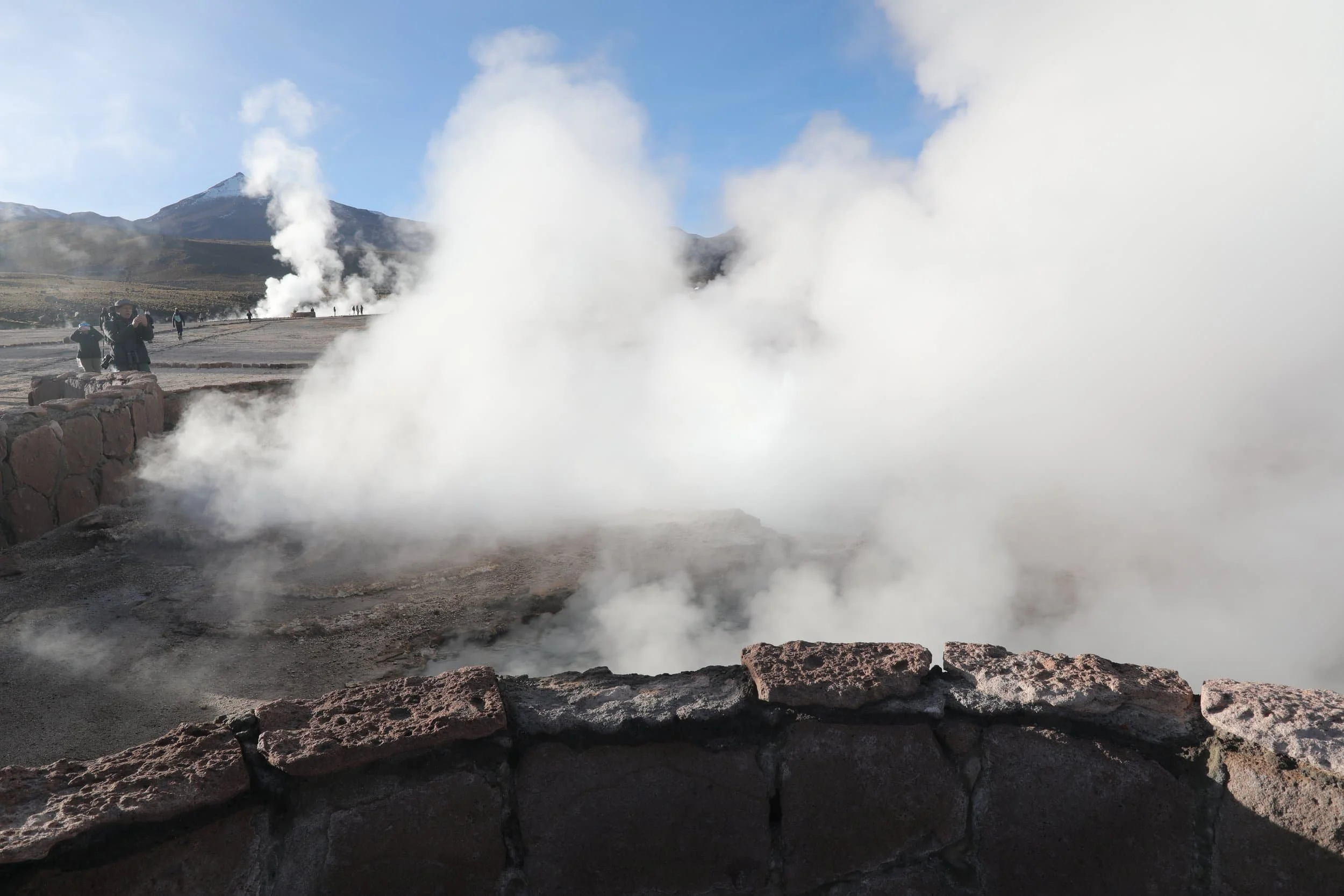 Powerful steam rising from the Assassin Geyser, surrounded by dark mineral formations at El Tatio in Chile.