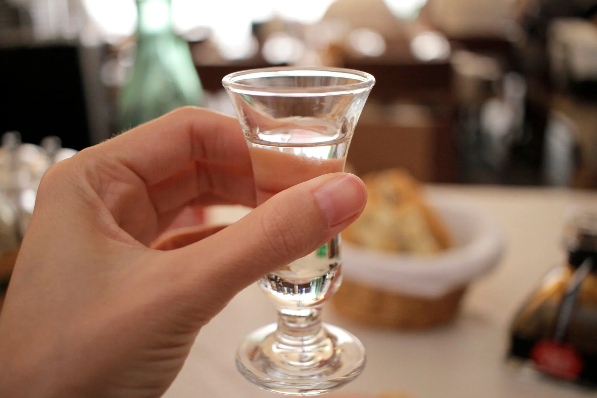 Hand holding small shot glass at restaurant in Hvar Island in Croatia